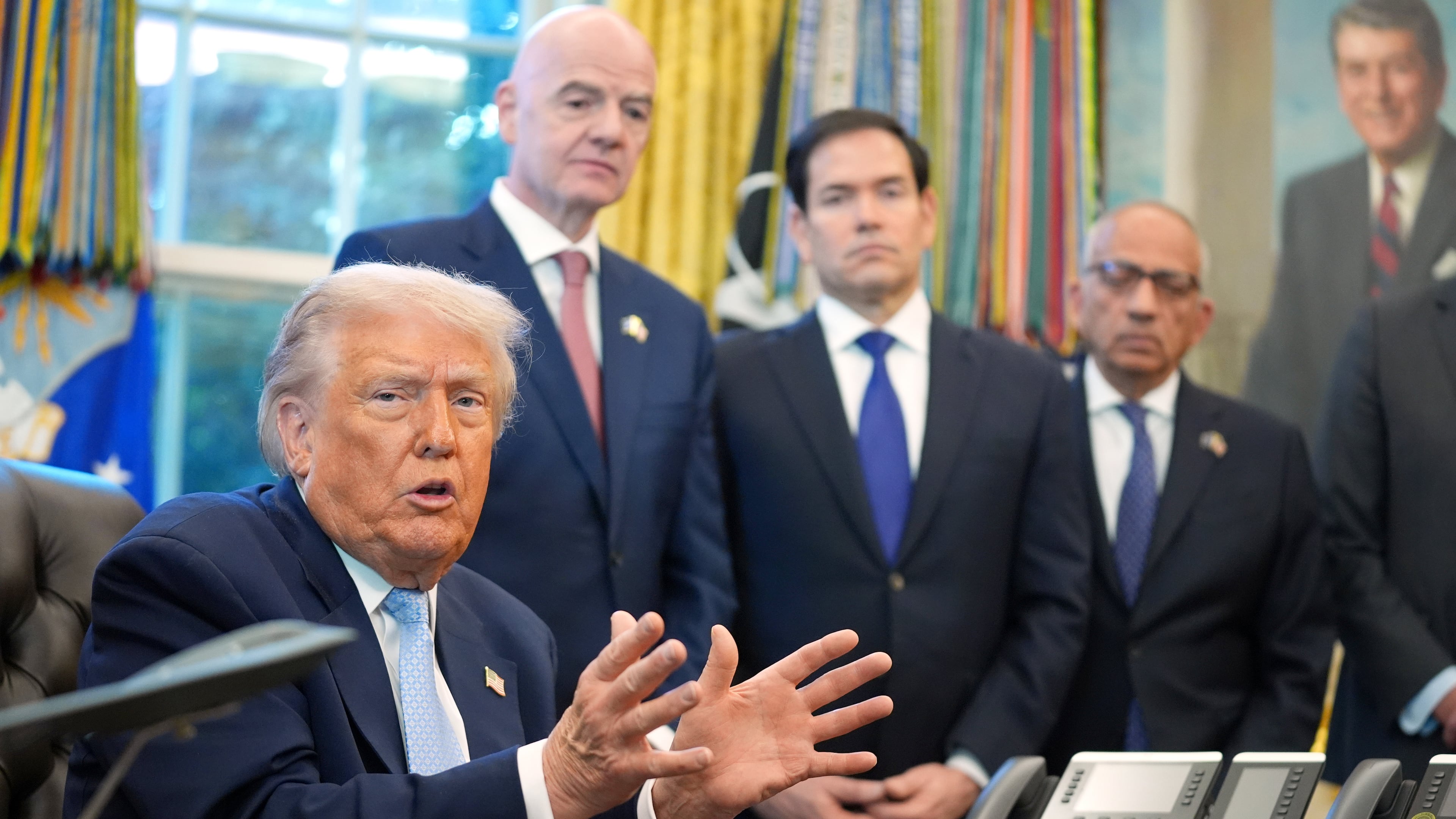 FILE - President Donald Trump answers questions from reporters during a meeting with the White House task force on the 2026 FIFA World Cup in the Oval Office of the White House, Monday, Nov. 17, 2025, in Washington, as FIFA President Gianni Infantino, Secretary of State Marco Rubio and FIFA senior adviser Carlos Cordeiro listen. (AP Photo/Evan Vucci, file)
