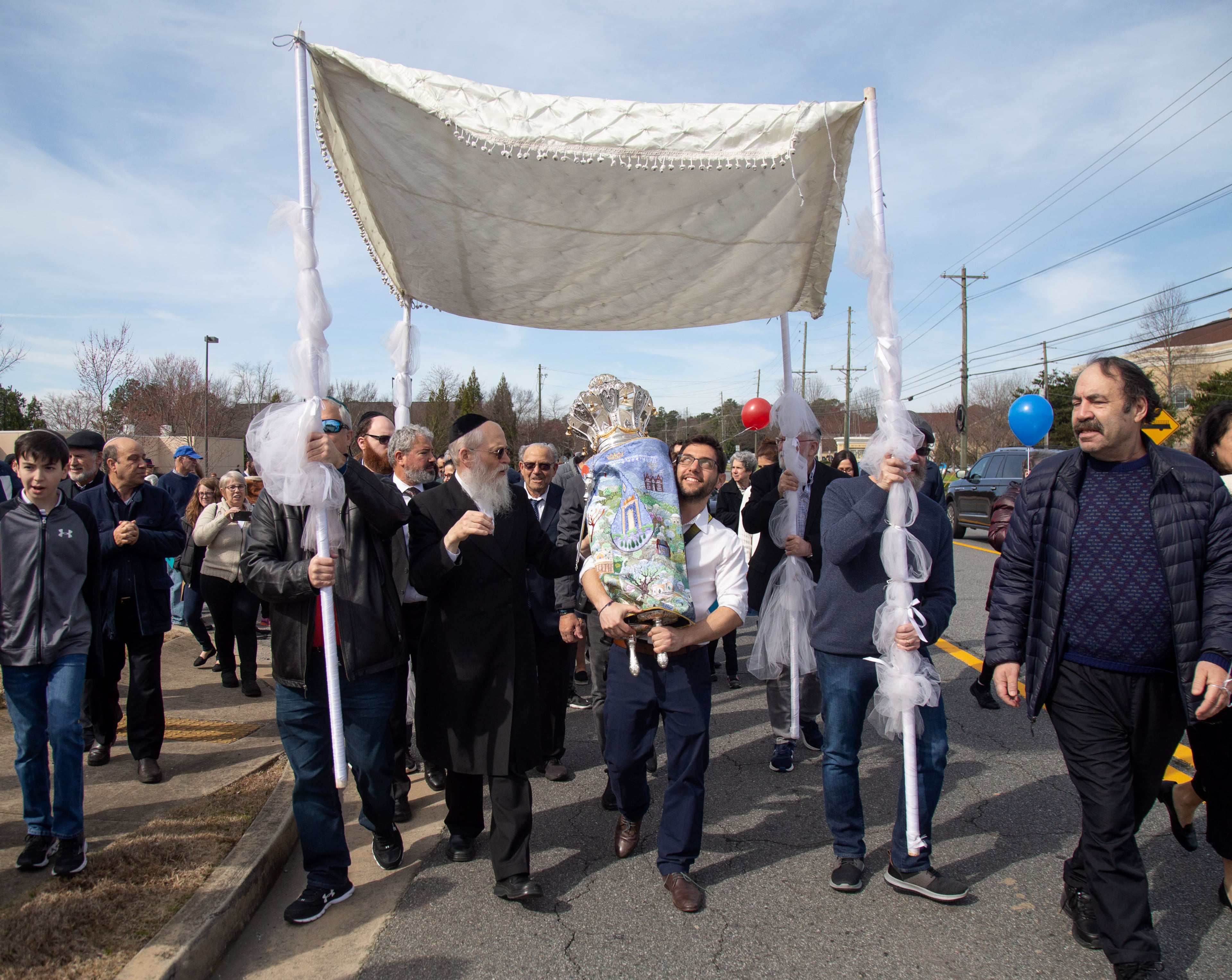 Men take turns marching down Lower Roswell Road, holding the special Torah scroll during a parade celebrating its completion at Chabad of Cobb on Sunday, March 8, 2020. (Photo: STEVE SCHAEFER / SPECIAL TO THE AJC)
