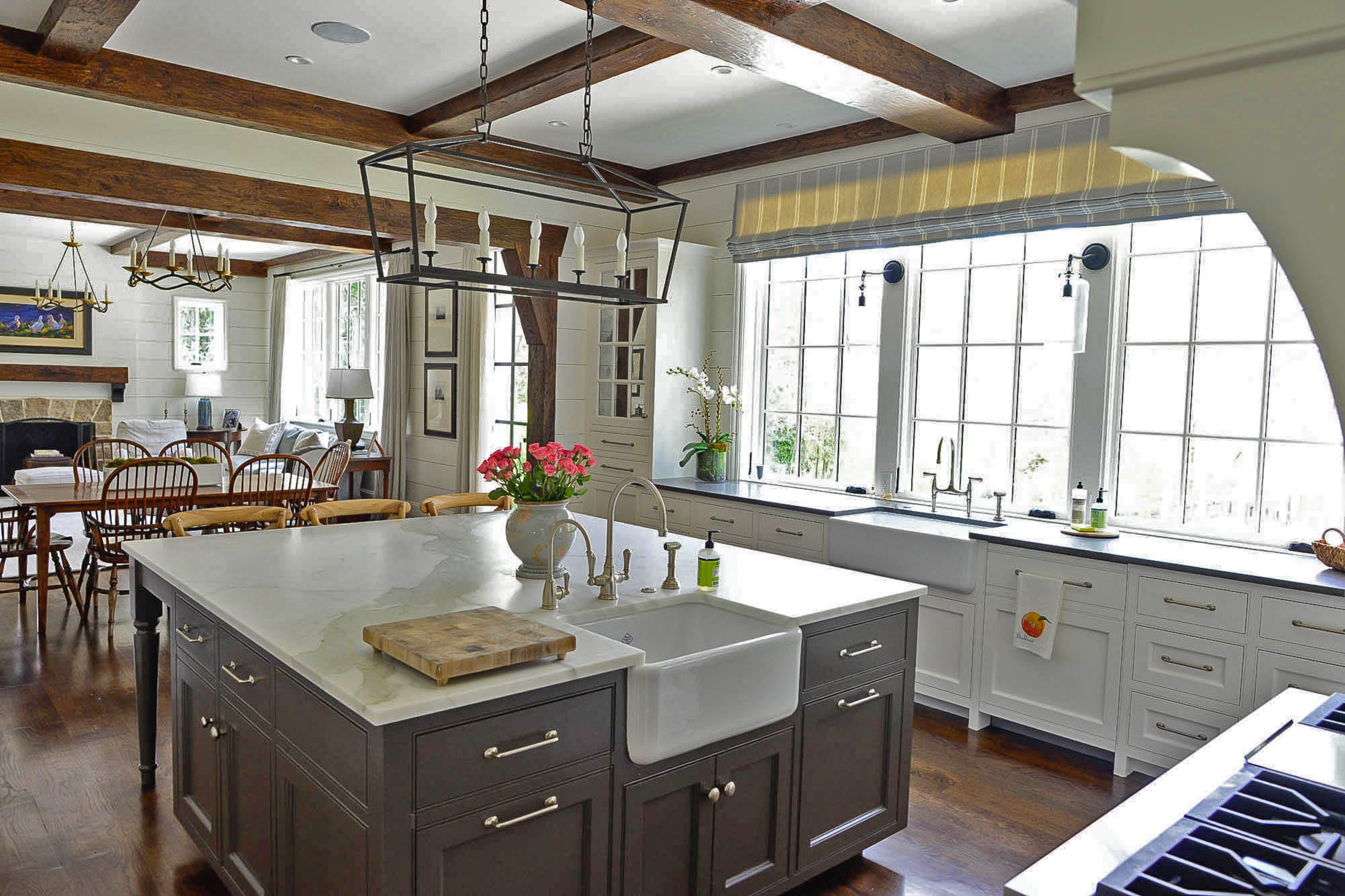 The island, with a second farmhouse-style sink, is painted Black Fox by Benjamin Moore. The kitchen, breakfast area and living room are open but the faux beams define the spaces.