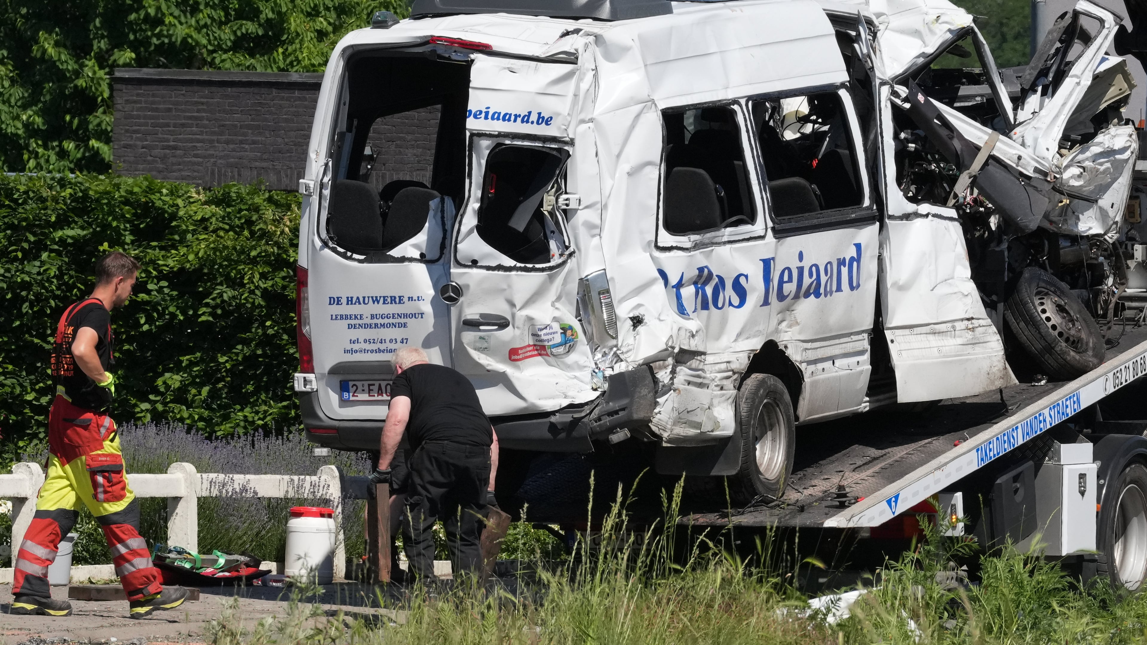 Emergency personnel work at a level crossing to move a van onto a flatbed truck after it collided with a train in Buggenhout, Belgium, Tuesday, May 26, 2026. (AP Photo/Marius Burgelman)