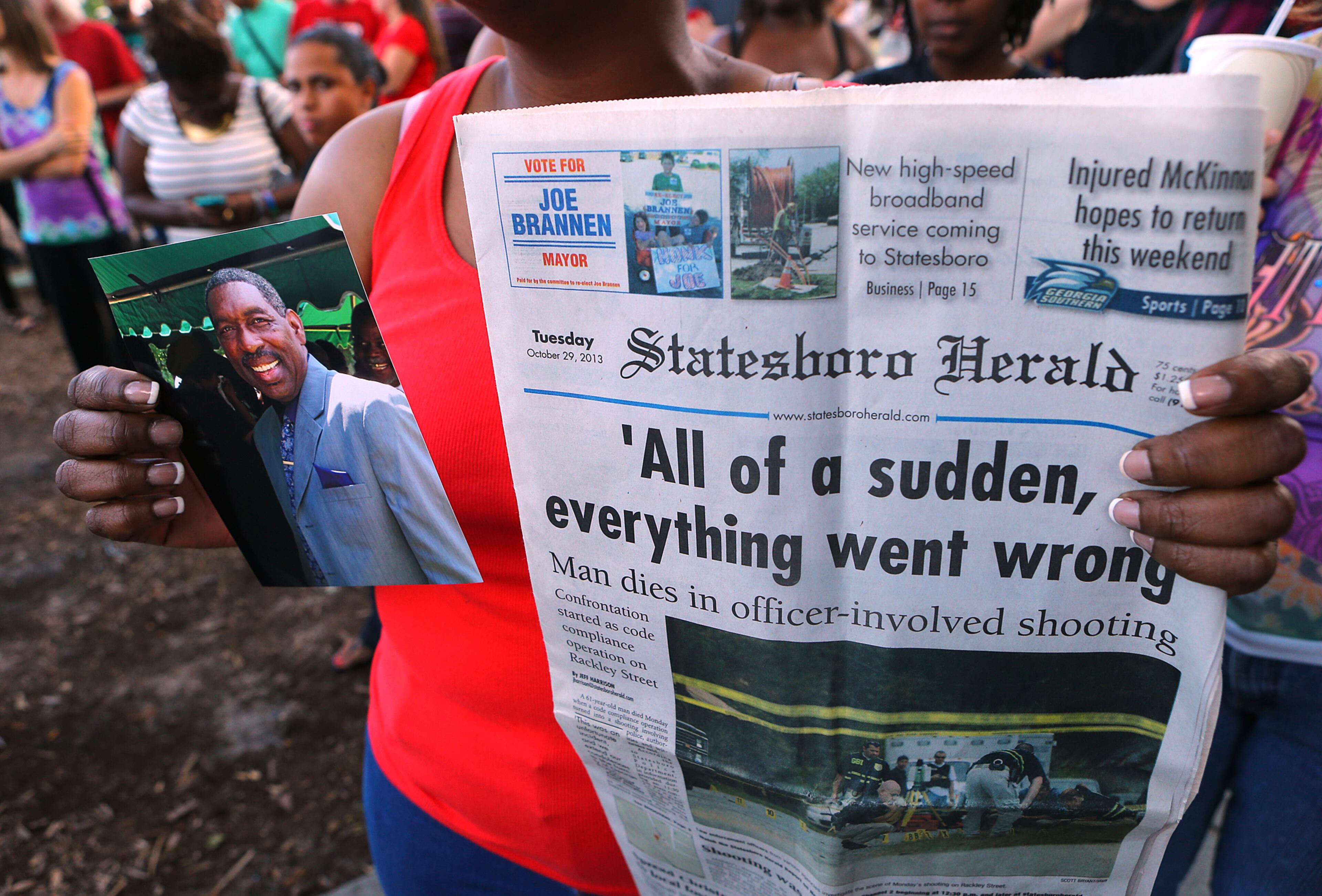 Brenda Owens, who says her dad George Pryor was killed in Statesboro in a police involved shooting, holds his picture and a copy of the newspaper while hundreds gather for a candlelight vigil and moment of silence protesting the police shooting of Michael Brown as part of a national observance on Aug. 14, 2014, in Decatur. CURTIS COMPTON / CCOMPTON@AJC.COM