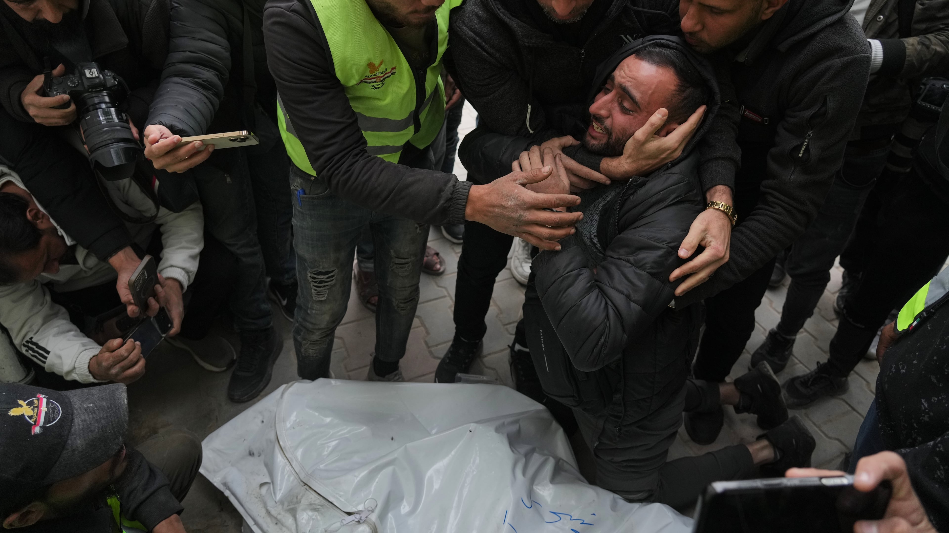 People mourn over the bodies of the Palestinian journalists Abd Shaat and Mohamed Qeshta, who were killed in an Israeli strike on a vehicle, before their funeral at Shifa Hospital, in Gaza City, Wednesday, Jan. 21, 2026. (AP Photo/Jehad Alshrafi)