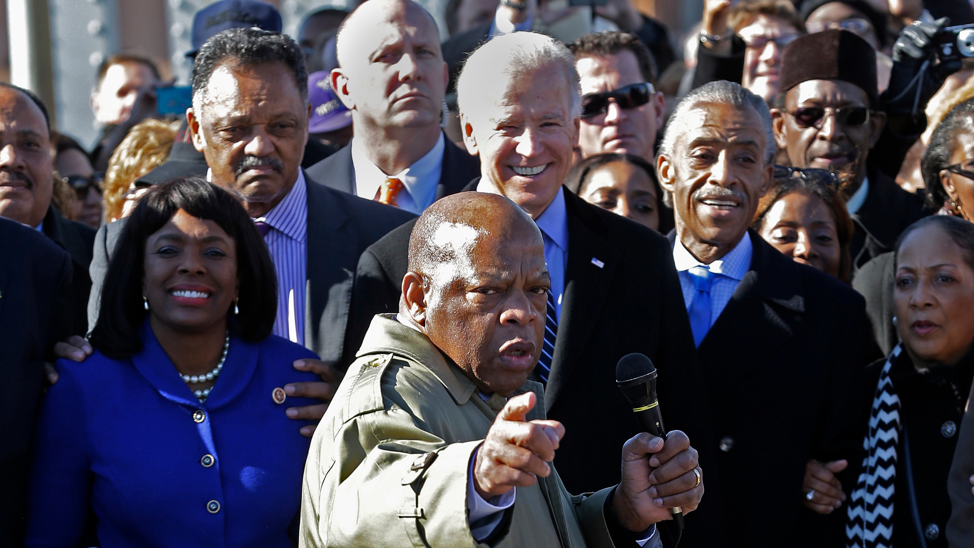 In this March 2013 file photo, U.S. Rep. John Lewis, D-Ga., points to where he and others were beaten 48 years ago when they tried to cross the Edmund Pettus Bridge during a civil rights march in Selma, Ala. At rear is Vice President Joe Biden. At left is U.S. Rep. Terri Sewell, D-Ala.; Jesse Jackson is second from left. (AP Photo/Dave Martin)
