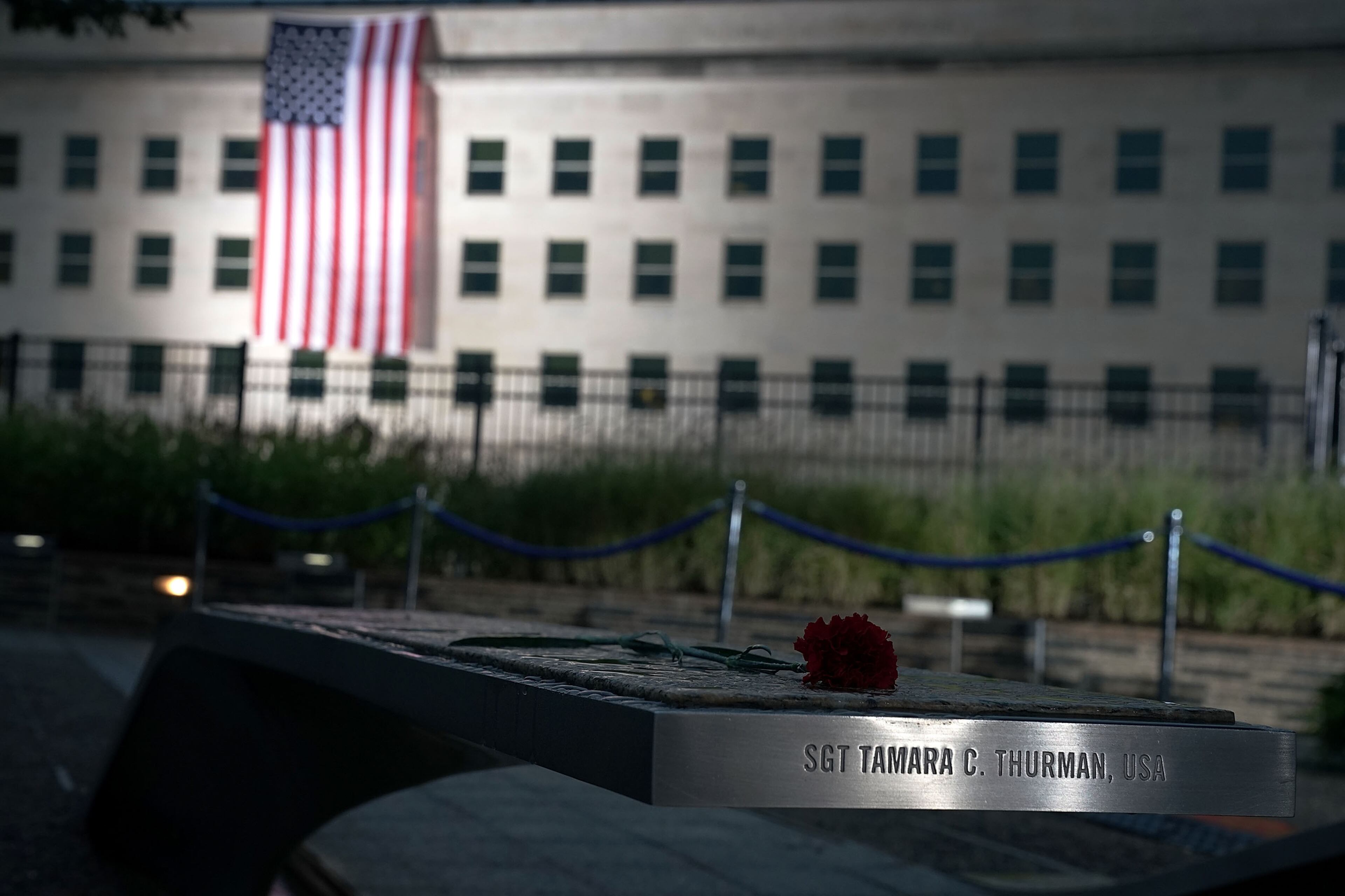 ARLINGTON, VA - SEPTEMBER 11: A carnation is placed on the bench of Sgt. Tamara C. Thurman at the National 9/11 Pentagon Memorial as an American flag is unfurled down the side of the Pentagon to mark the 17th anniversary of the 9/11 terror attacks September 11, 2018 in Arlington, Virginia. The nation observed 9/11 terror attacks that killed nearly 3000 people on American soil in 2001. (Photo by Alex Wong/Getty Images)