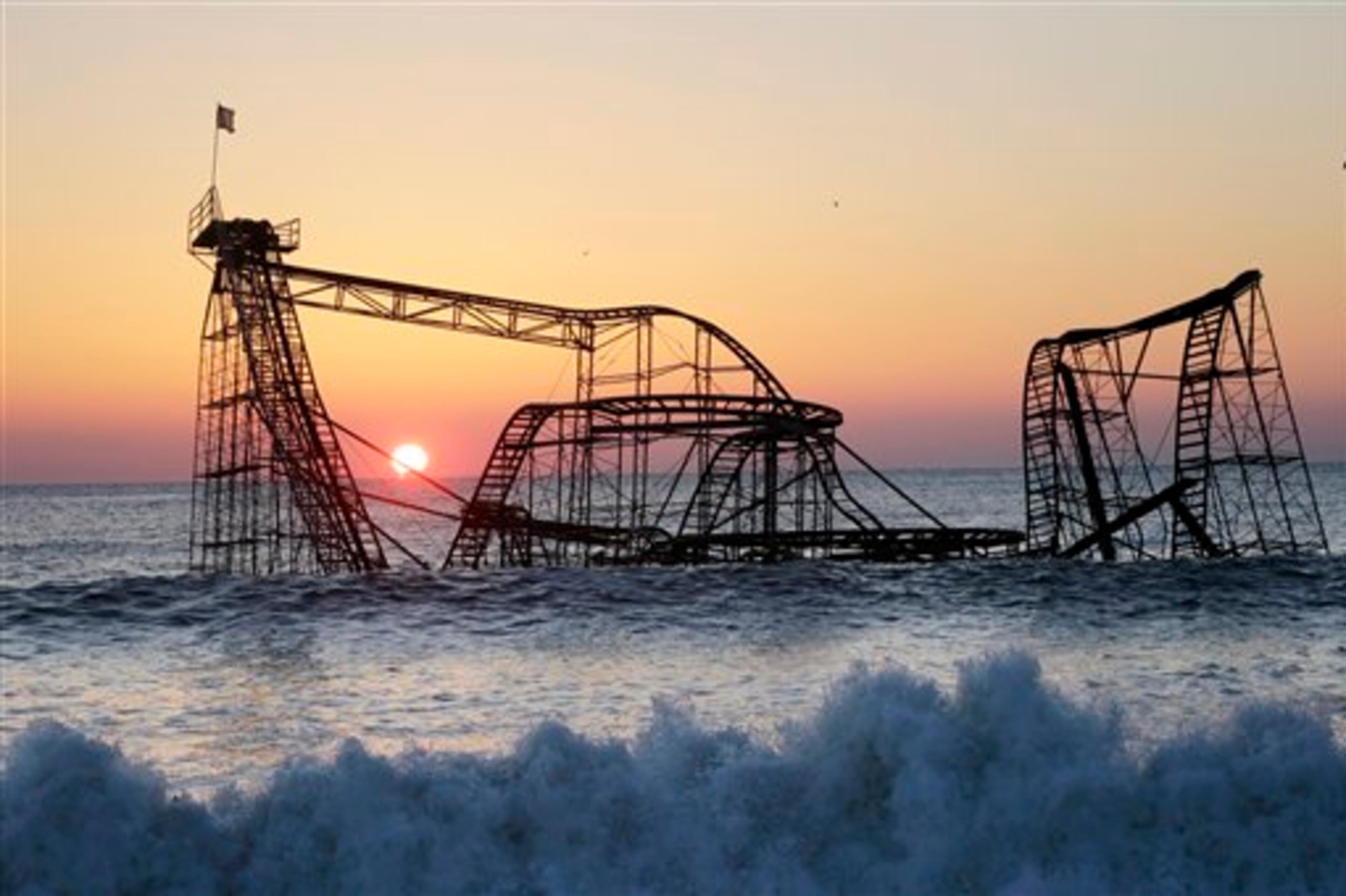 The sun rises in Seaside Heights, N.J., Monday, Feb. 25, 2013, behind the Jet Star Roller Coaster which has been sitting in the ocean after part of the Funtown Pier was destroyed during Superstorm Sandy. The private owners of the amusement pier that collapsed in Seaside Heightsare working with insurers to devise a plan to dismantle the ride and get it out of the ocean. (AP Photo/Mel Evans)