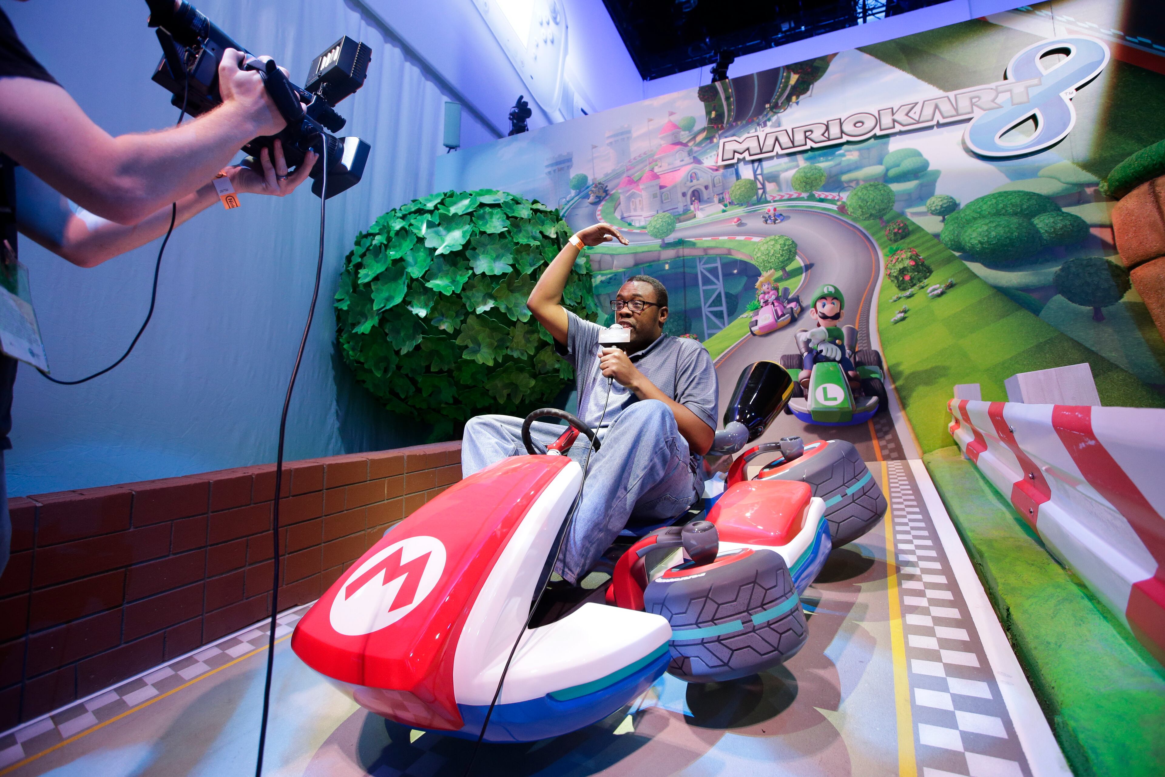 Reporter Andre Meadows works while sitting in a replica of the Mario Kart at the Nintendo booth during the Electronic Entertainment Expo in Los Angeles, Tuesday, June 11, 2013. (AP Photo/Jae C. Hong)