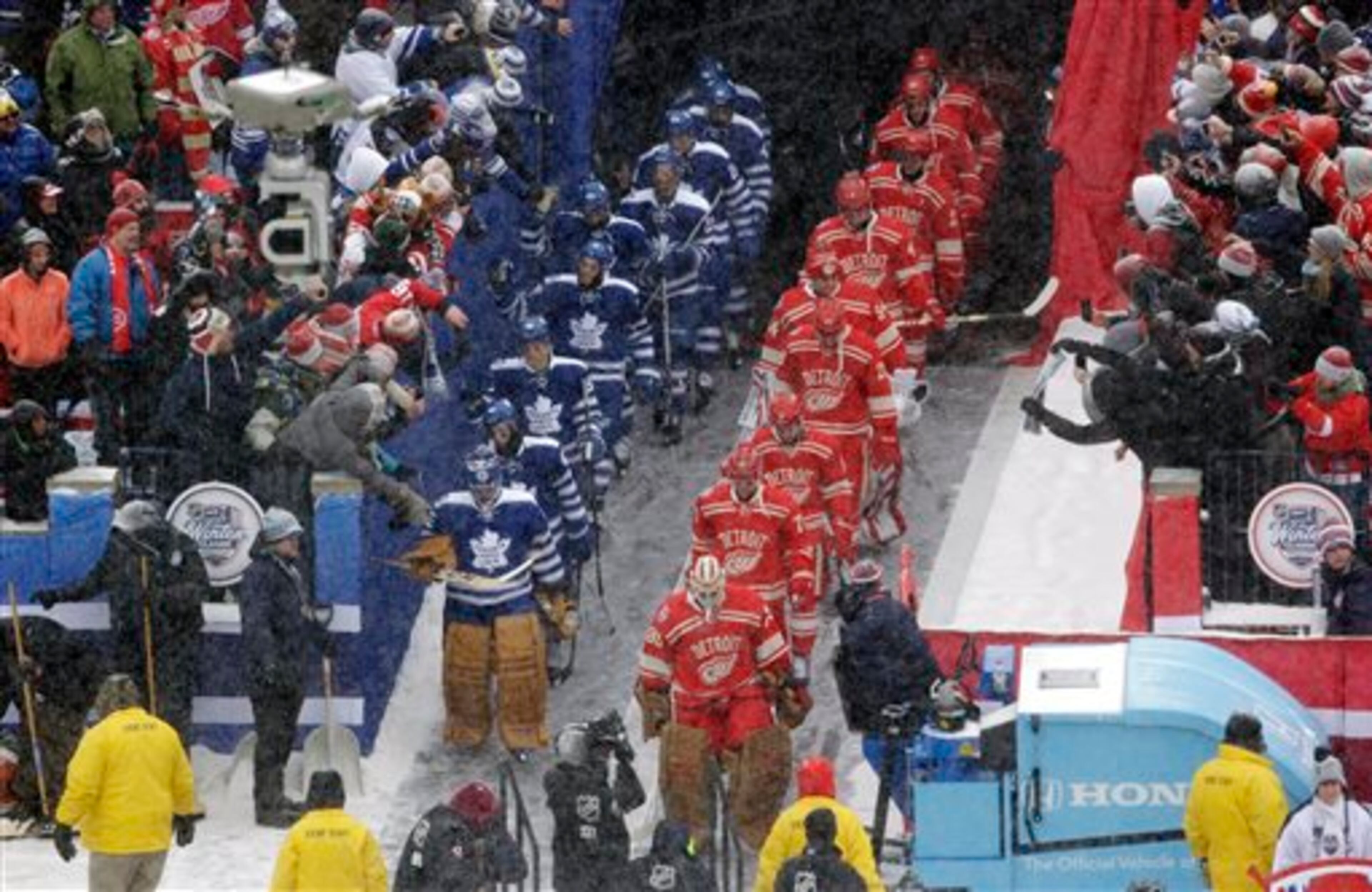 The Detroit Red Wings, right, and the Toronto Maple Leafs walk out to the rink as a light snow falls at Michigan Stadium for the start of the Winter Classic outdoor NHL hockey game in Ann Arbor, Mich., Wednesday, Jan. 1, 2014. (AP Photo/Carlos Osorio)