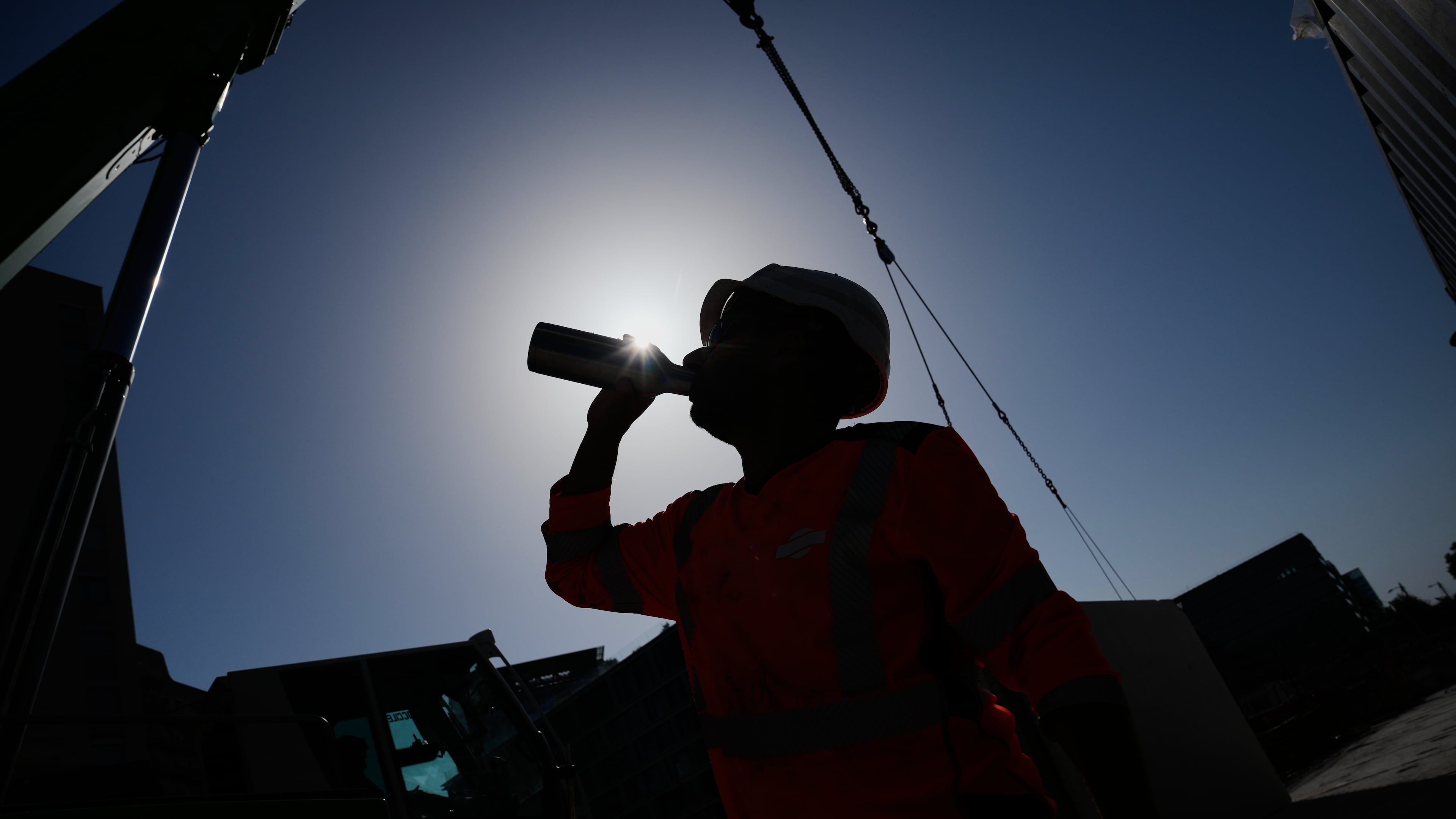 FILE - A worker drinks water on a construction site during high temperatures in Boulogne Billancourt, outside Paris, June 24, 2026. (AP Photo/Christophe Ena)