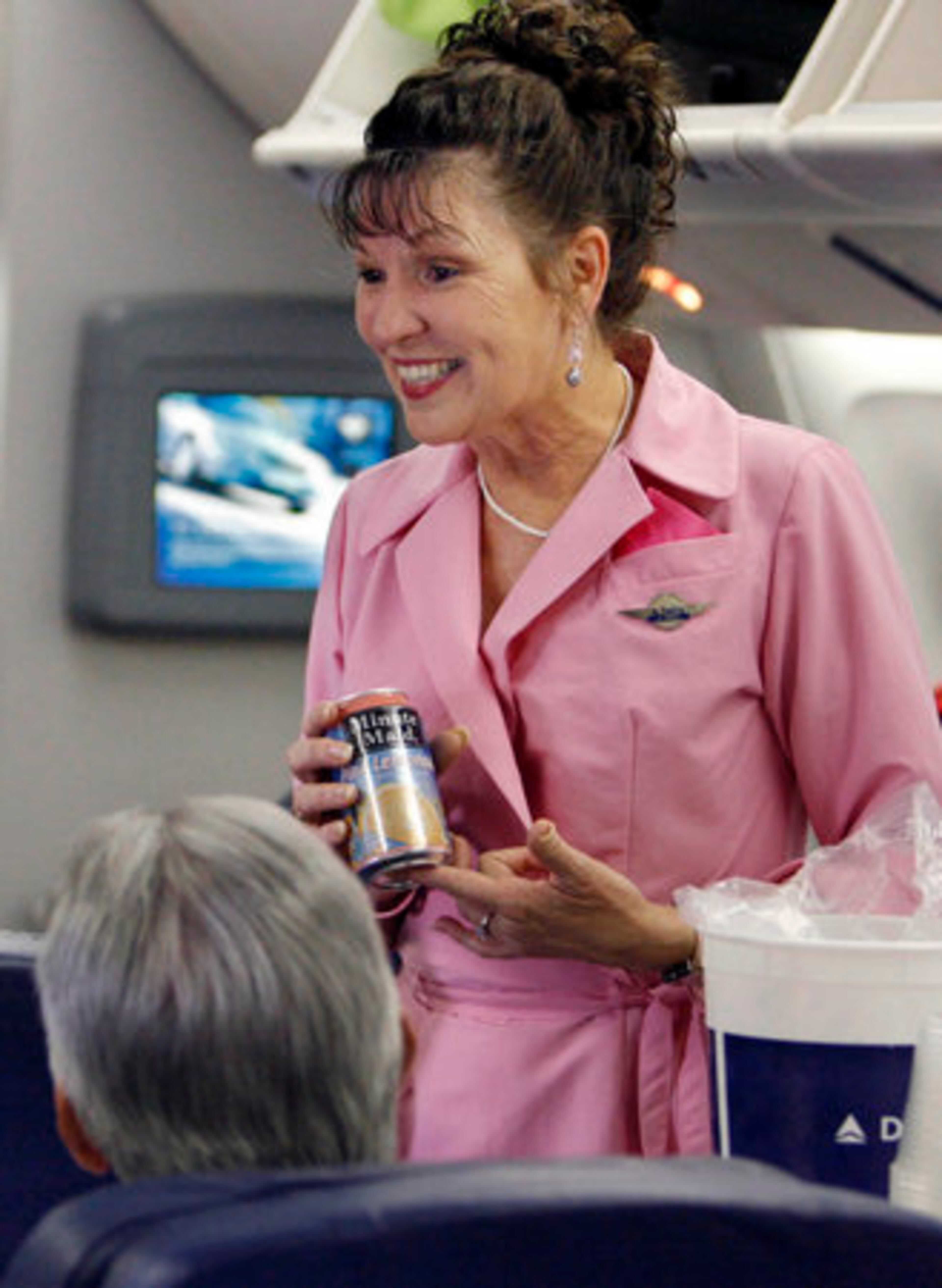 Veteran Delta flight attendant Alice Ramsey, a breast cancer survivor, serves pink lemonade to passengers on a Delta flight to Honolulu, Hawaii, before departing Atlanta Wednesday. All Delta flight attendants are wearing the pink dresses she had sewn to raise funds for the Breast Cancer Research Foundation.