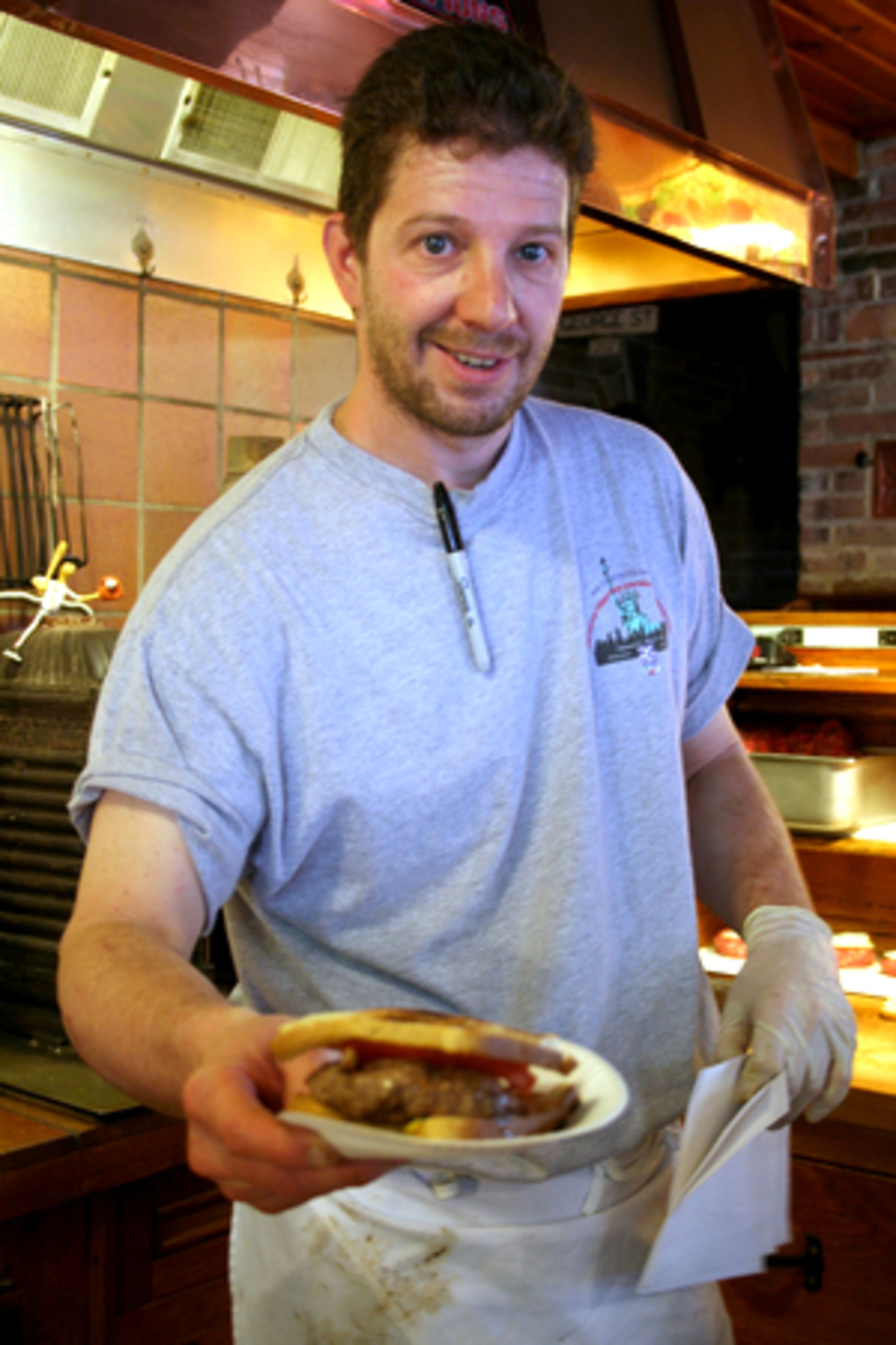 Jeff Lassen, a fourth-generation family member at Louis' Lunch, serves up one of the tiny restaurant's famous hamburger sandwiches. The restaurant created its iconic sandwich in 1900.
