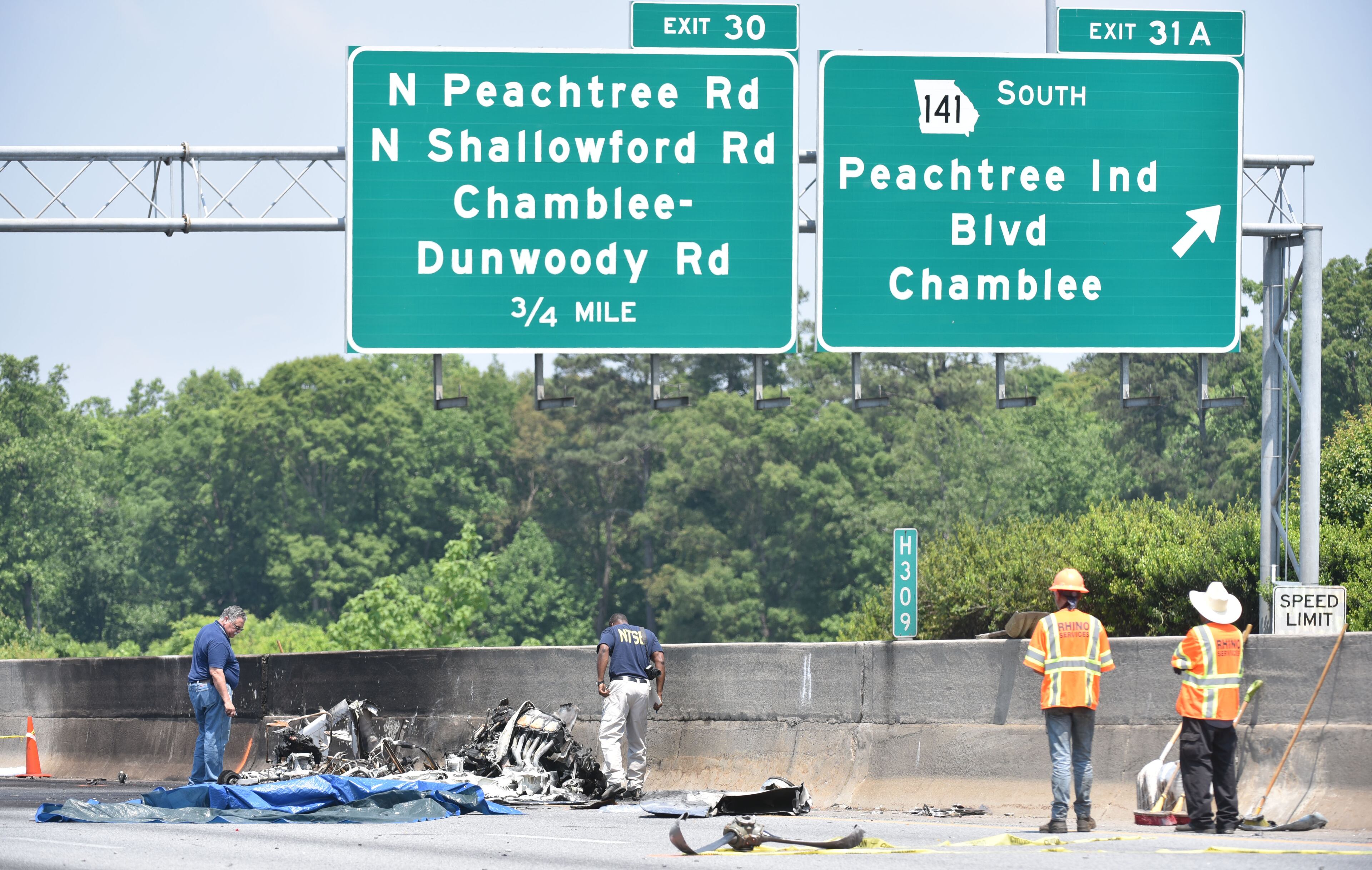 May 8, 2015 Atlanta - NTSB Investigators examine airplane parts on I-285 at Peachtree Industrial Boulevard, where four people died aboard a small plan, on Friday, May 8, 2015. Traffic was shut down in both directions. Three men and one woman were killed in the crash, according to Channel 2 Action News. The National Transportation Safety Board is in charge of the investigation and will determine probable cause. HYOSUB SHIN / HSHIN@AJC.COM