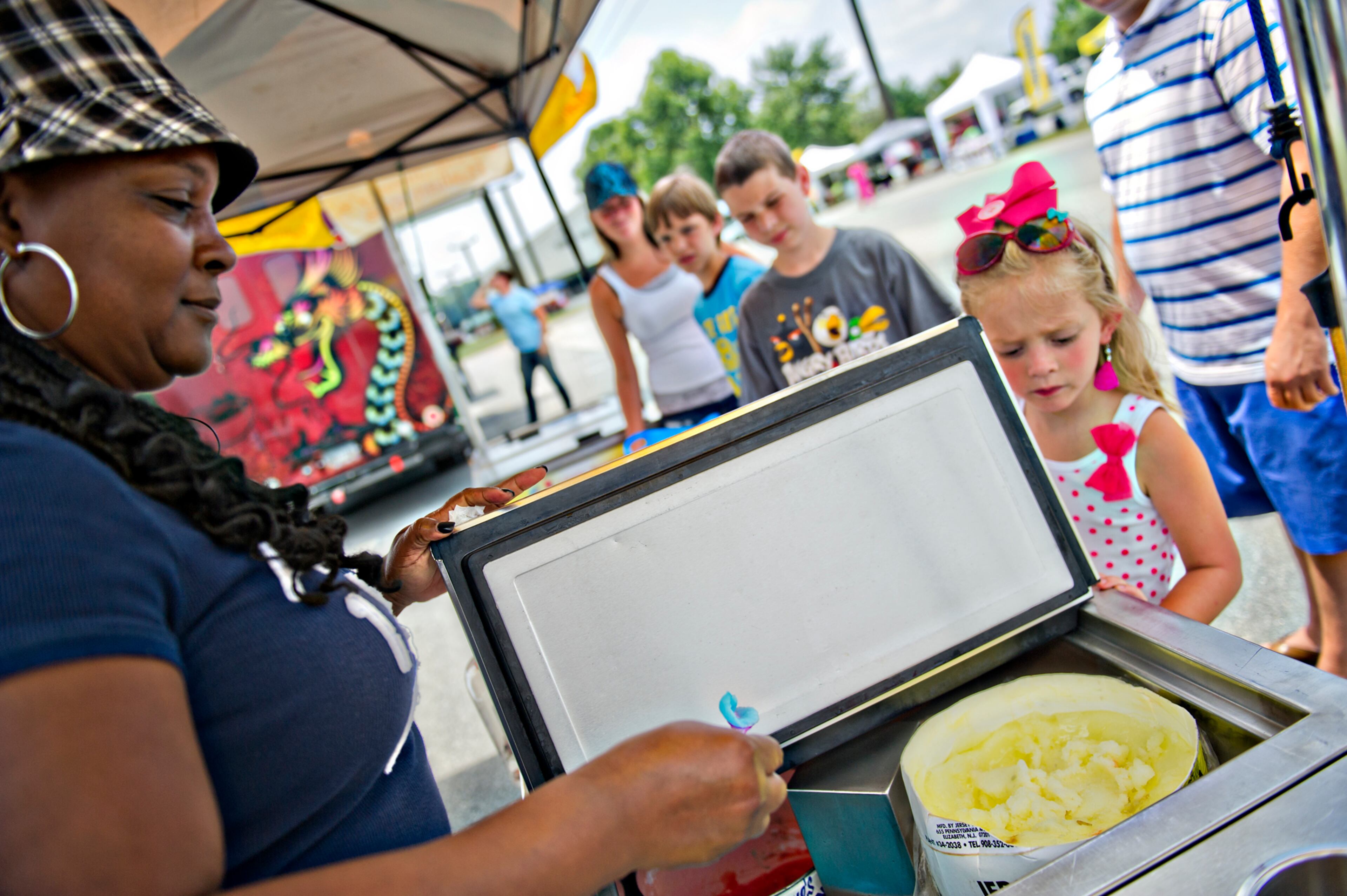 July 6, 2014 Marietta - Teresa Davis-Howard (left) hands a spoonful of blueberry Italian ice to Madison Spillers (right) as her family peruses the food options during the Atlanta Food Festival at Jim R. Miller Park in Marietta on Sunday, July 6, 2014. JONATHAN PHILLIPS / SPECIAL