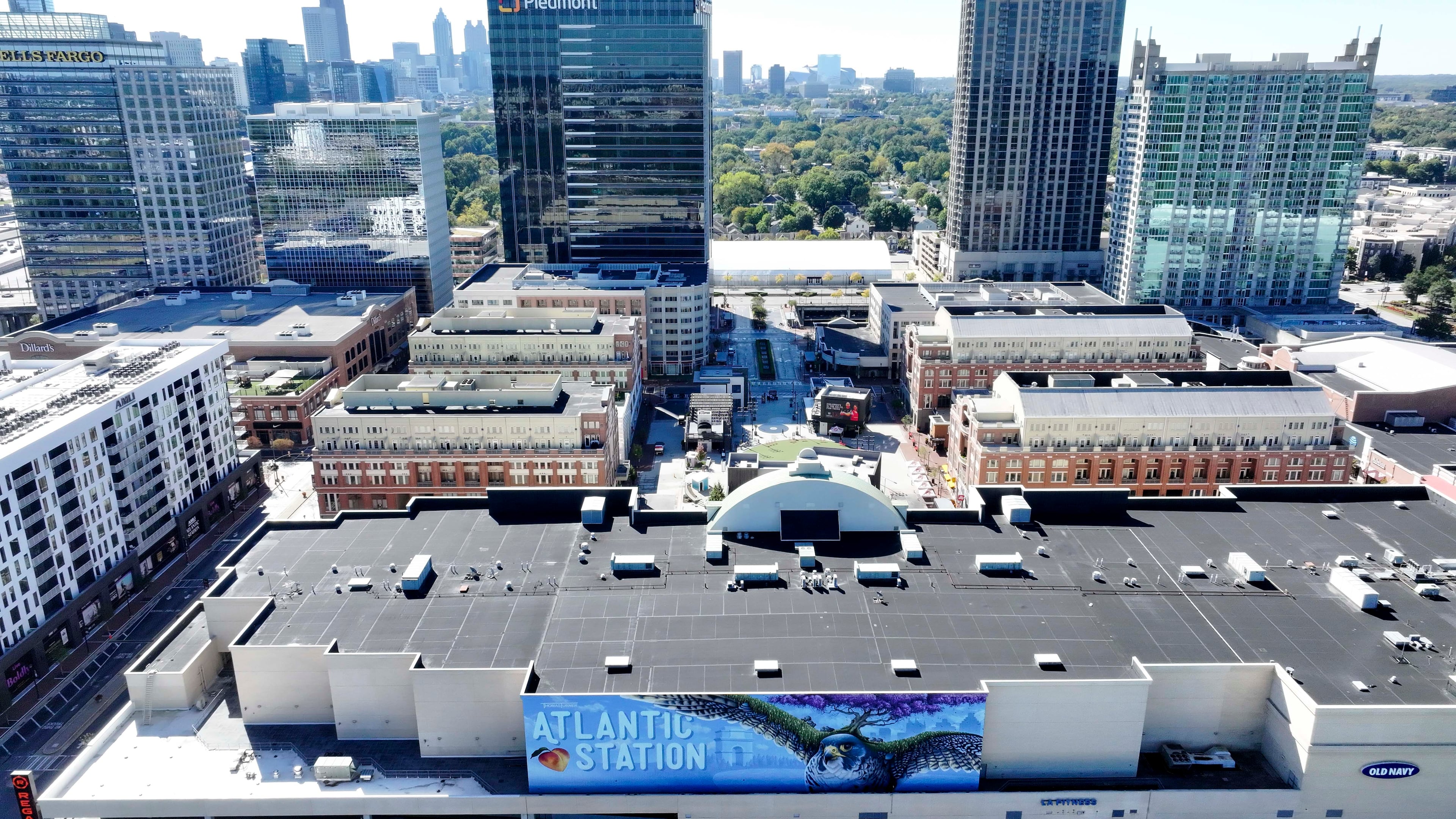 An aerial image shows the main square at Atlantic Station with the Atlanta skyline in the background on Thursday, Oct. 16, 2025. The shopping district is celebrating 20 years of dedication to hospitality and entertainment, an area that has significantly shaped the local landscape. (Miguel Martinez/AJC)
