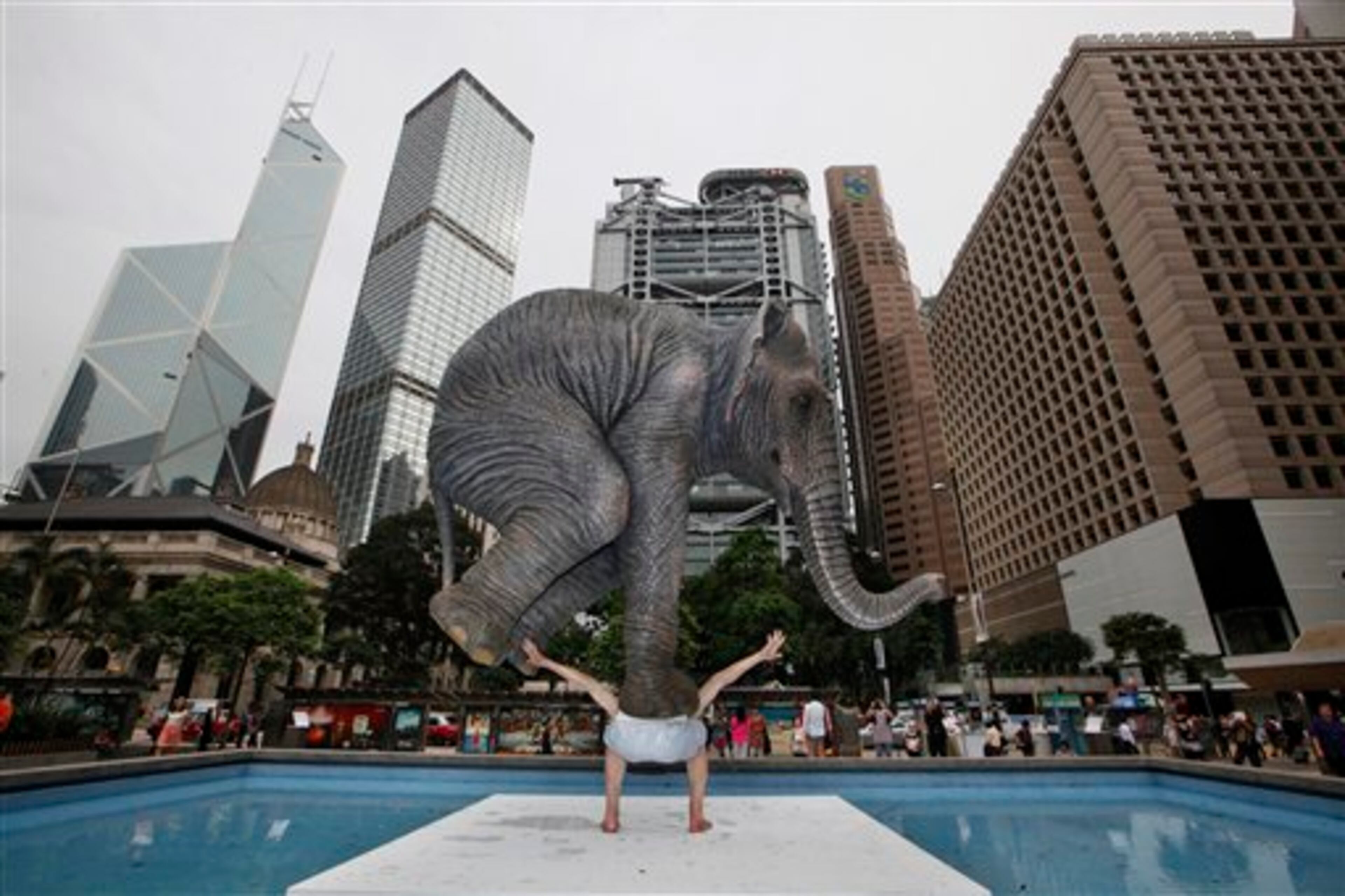 A five meters high sculpture "Pentateuque," created by Contemporary French artist Fabien Merelle, is displayed in Central, business district of Hong Kong, Tuesday, May 21, 2013. The artwork brings to real life the fantastical and seemingly impossible act of an average man balancing a gigantic elephant. The elephant and the man are modeled on one at the Singapore Zoo and on the artist himself. (AP Photo/Kin Cheung)