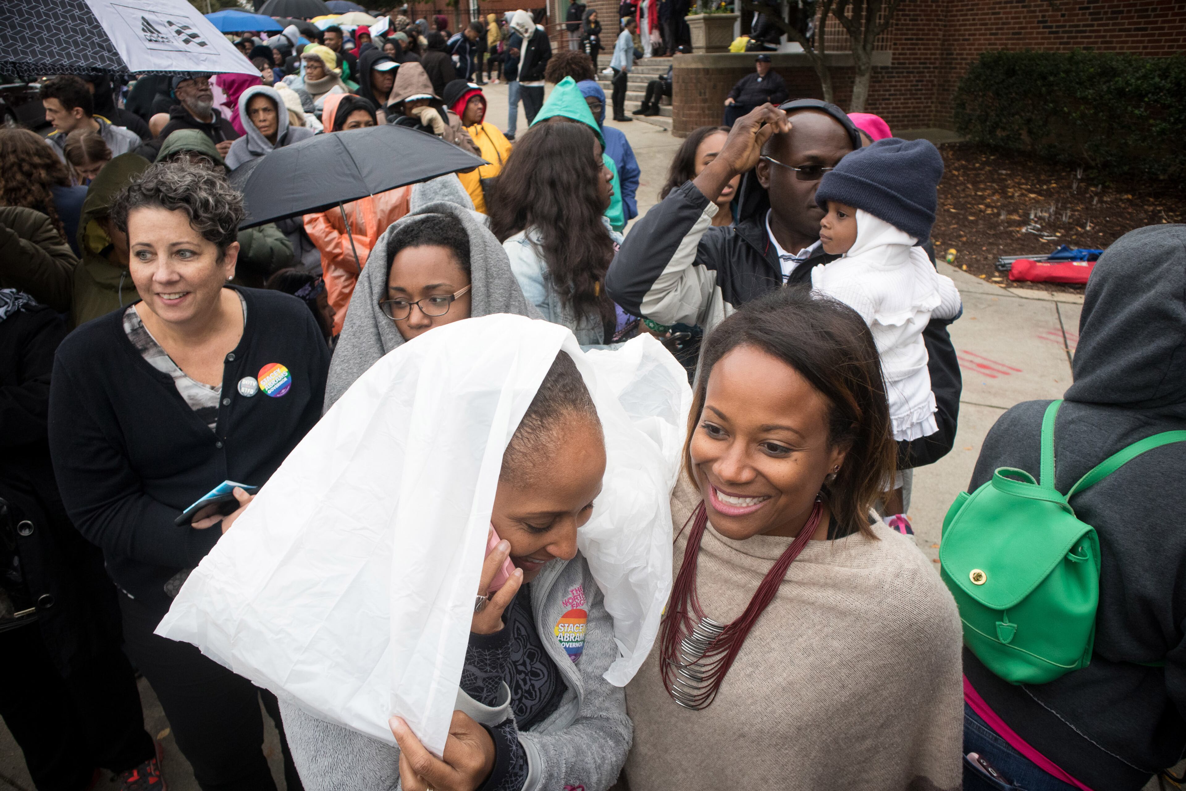 Katrina Blasingame (L) and Julia Demetrius try to stay dry while standing in line to see President Obama and Democratic Gubernatorial Nominee Stacey Abrams speak at the Forbes Arena at Morehouse College, in Atlanta, GA Friday, November 2, 2018. STEVE SCHAEFER / SPECIAL TO THE AJC