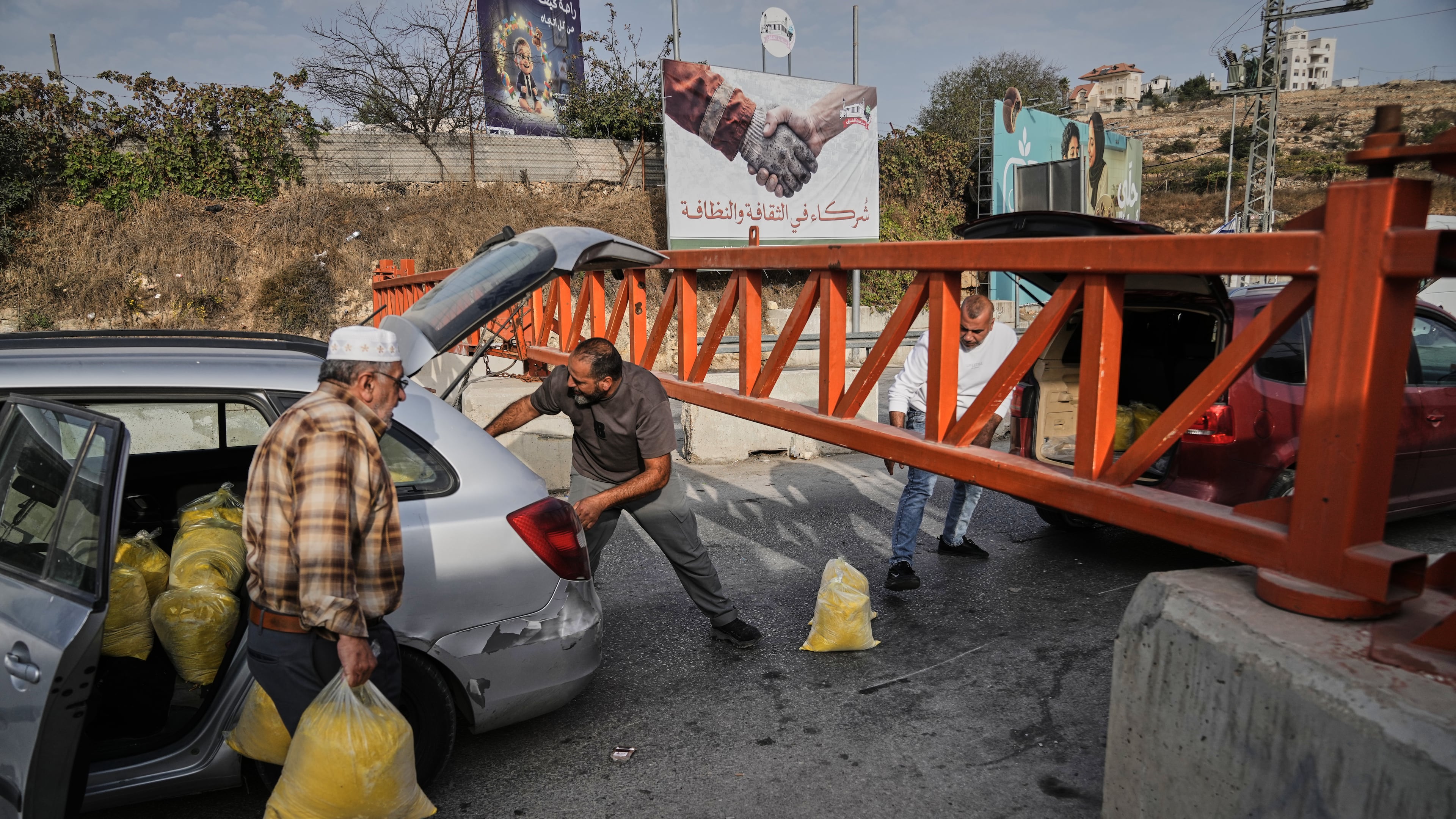 Palestinians transport bags of semolina past a military gate closed to vehicles during an Israeli army operation in Hebron, in the occupied West Bank, Saturday, Oct. 24, 2026, a day after a Palestinian shooting attack in the area. (AP Photo/Mahmoud Illean)
