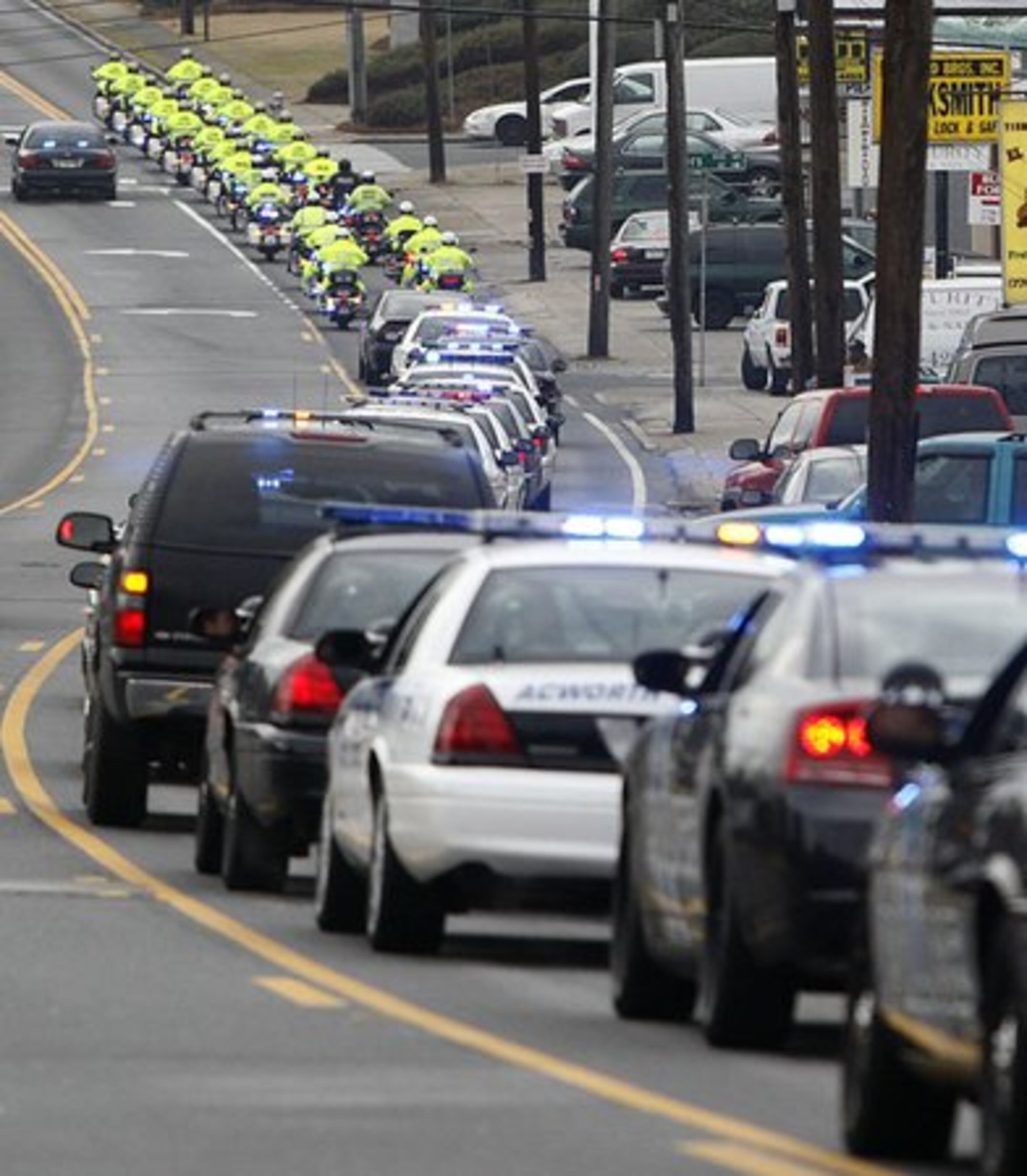 The procession of police vehicles snakes along Roswell Street toward Marietta Square.