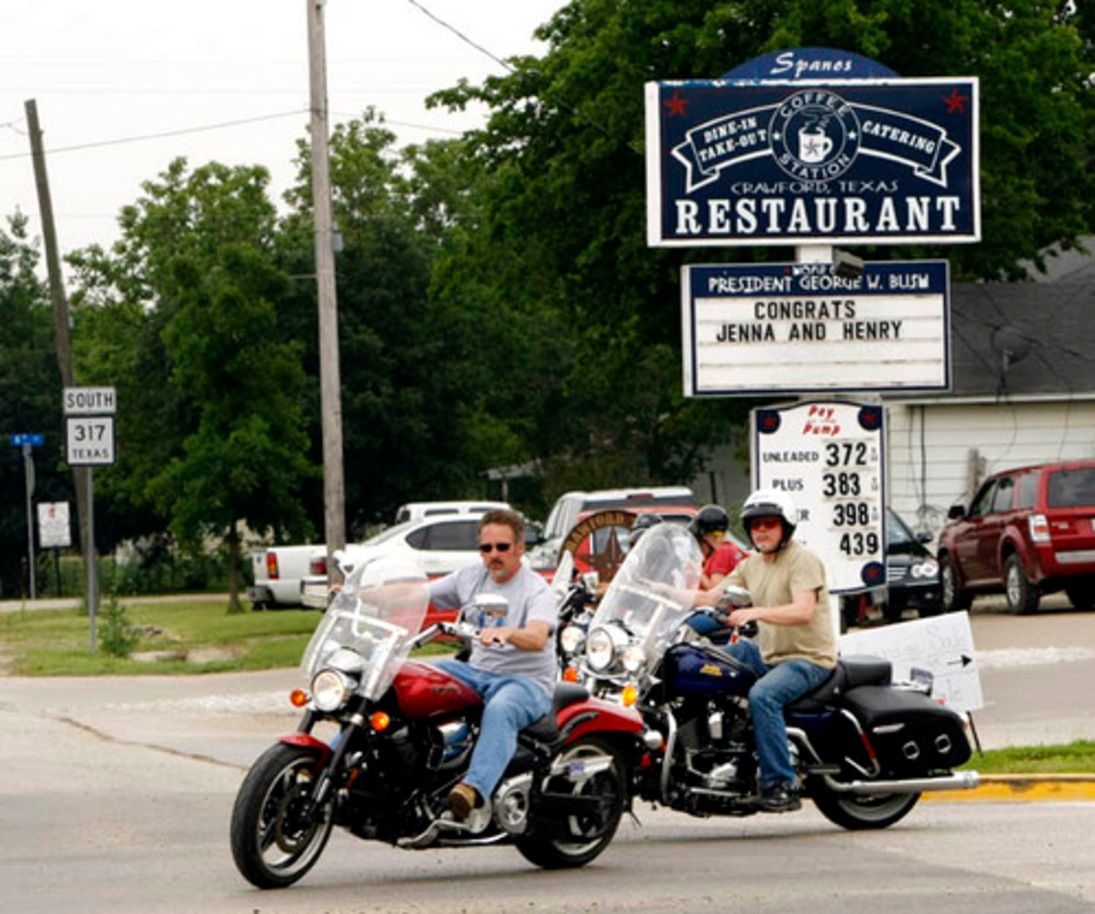 Motorcycles ride past a sign congratulating Jenna Bush and Henry Hager on their upcoming wedding.