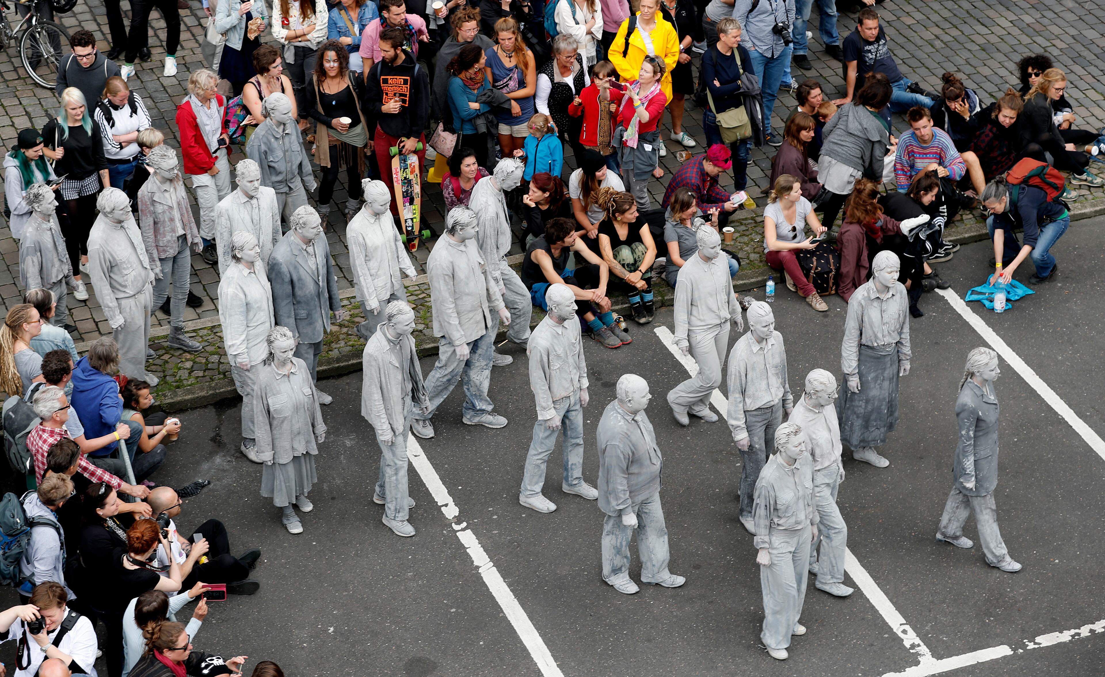 HAMBURG, GERMANY - JULY 05: Prostestors dressed-up in grey clothes like Zombies attend an arts performance called '1000 Gestalten' demonstration prior the upcoming G20 summit on July 5, 2017 in Hamburg, northern Germany. In a two-hour show hundreds of actors took part in a creative public appeal for more humanity and self-responsibility ahead of the upcoming G20 summit. The G20 economic summit takes place in Hamburg July 7-8. (Photo by Friedemann Vogel-Pool/Getty Images)