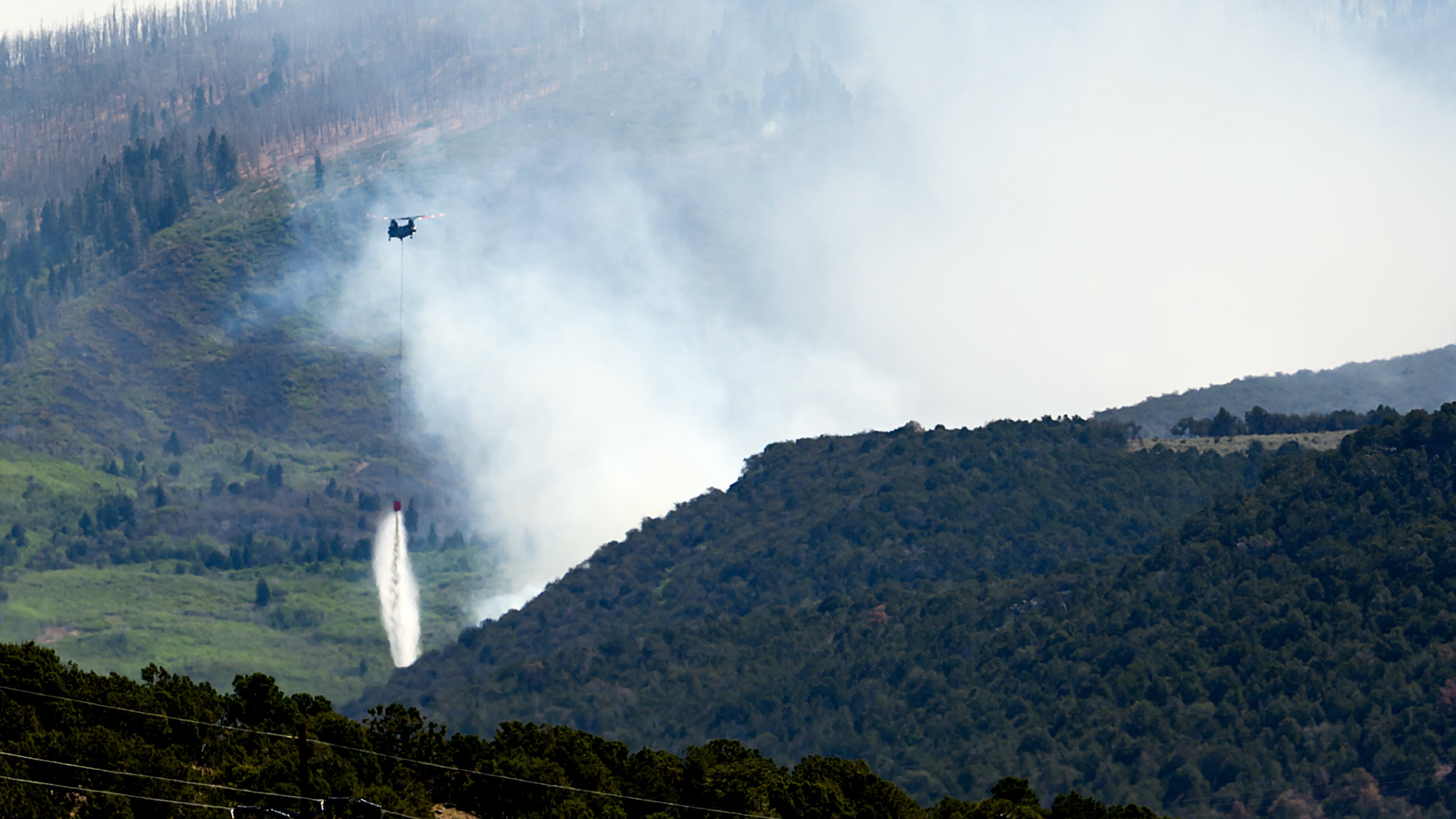 A helicopter drops water on the Cottonwood Fire burning near Beaver, Utah, on Saturday, June 27, 2026. (AP Photo/Noah Berger)