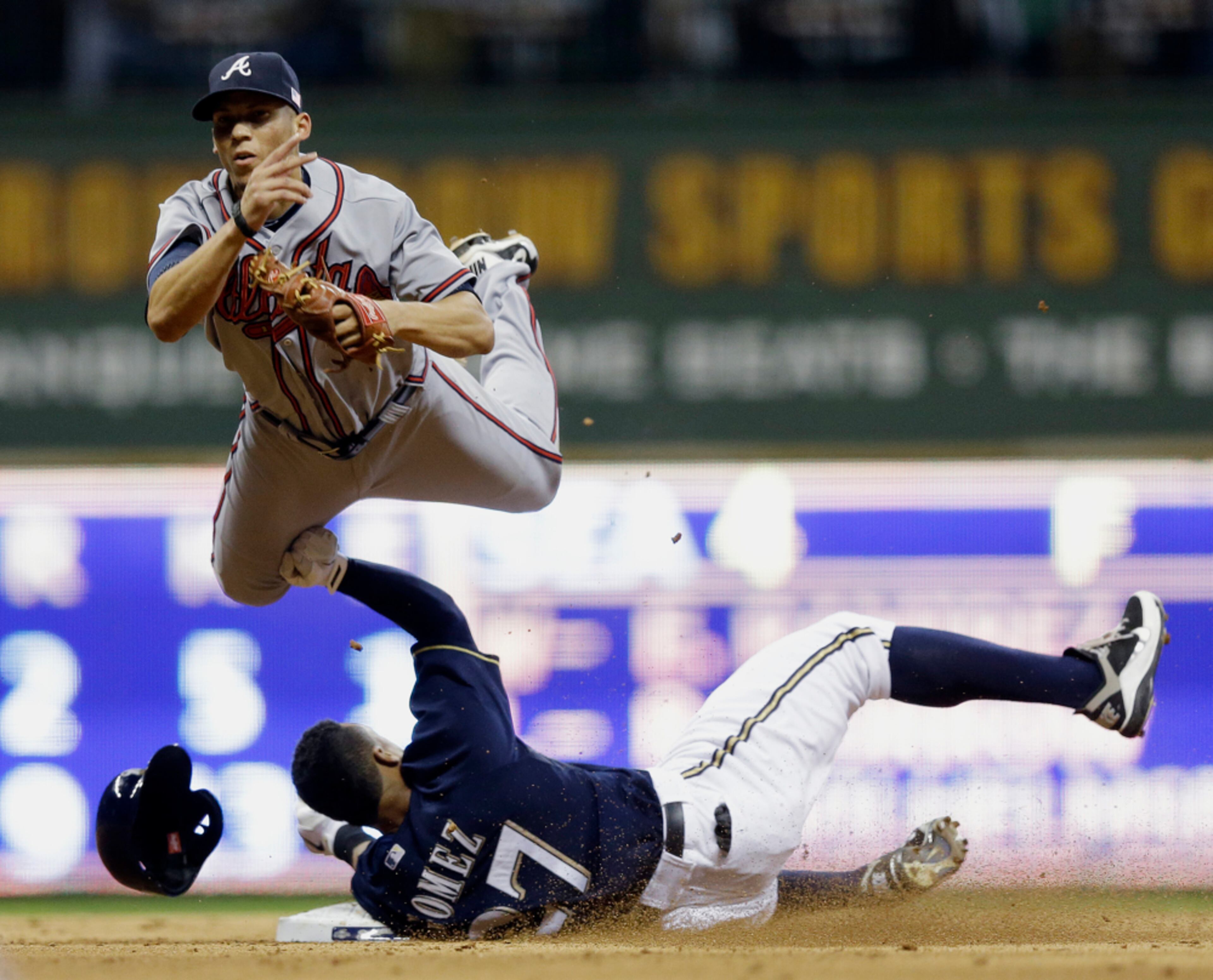 FLYING HIGH--Atlanta Braves' Andrelton Simmons leaps over Milwaukee Brewers' Carlos Gomez (27) as he tries to turn a double play on a ball hit by Jean Segura during the seventh inning of a baseball game Tuesday, Sept. 11, 2012, in Milwaukee. Segura beat the throw.