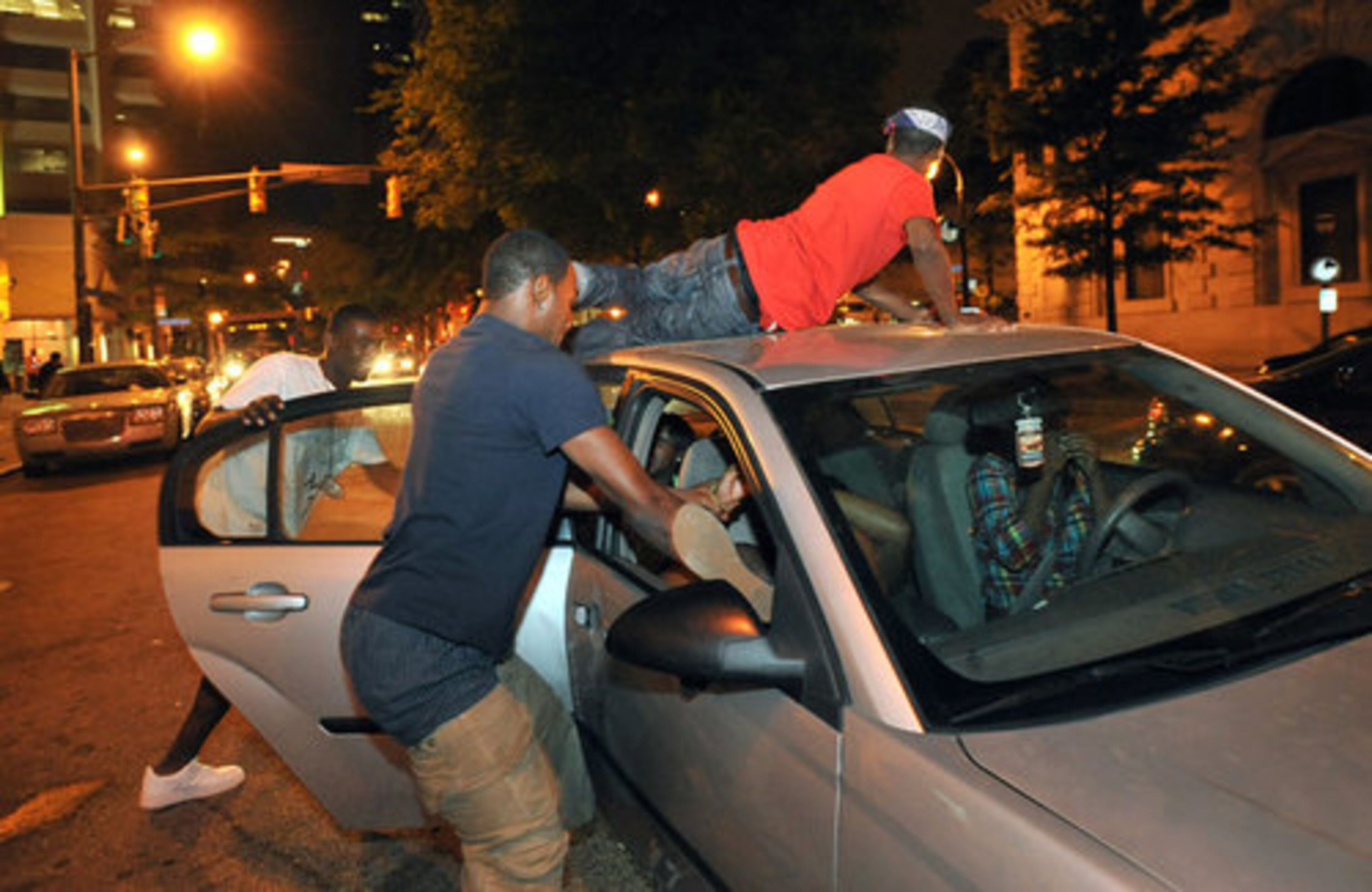 Freaknik revelers jump on a car Saturday night on Marietta Street near the Underground Atlanta.