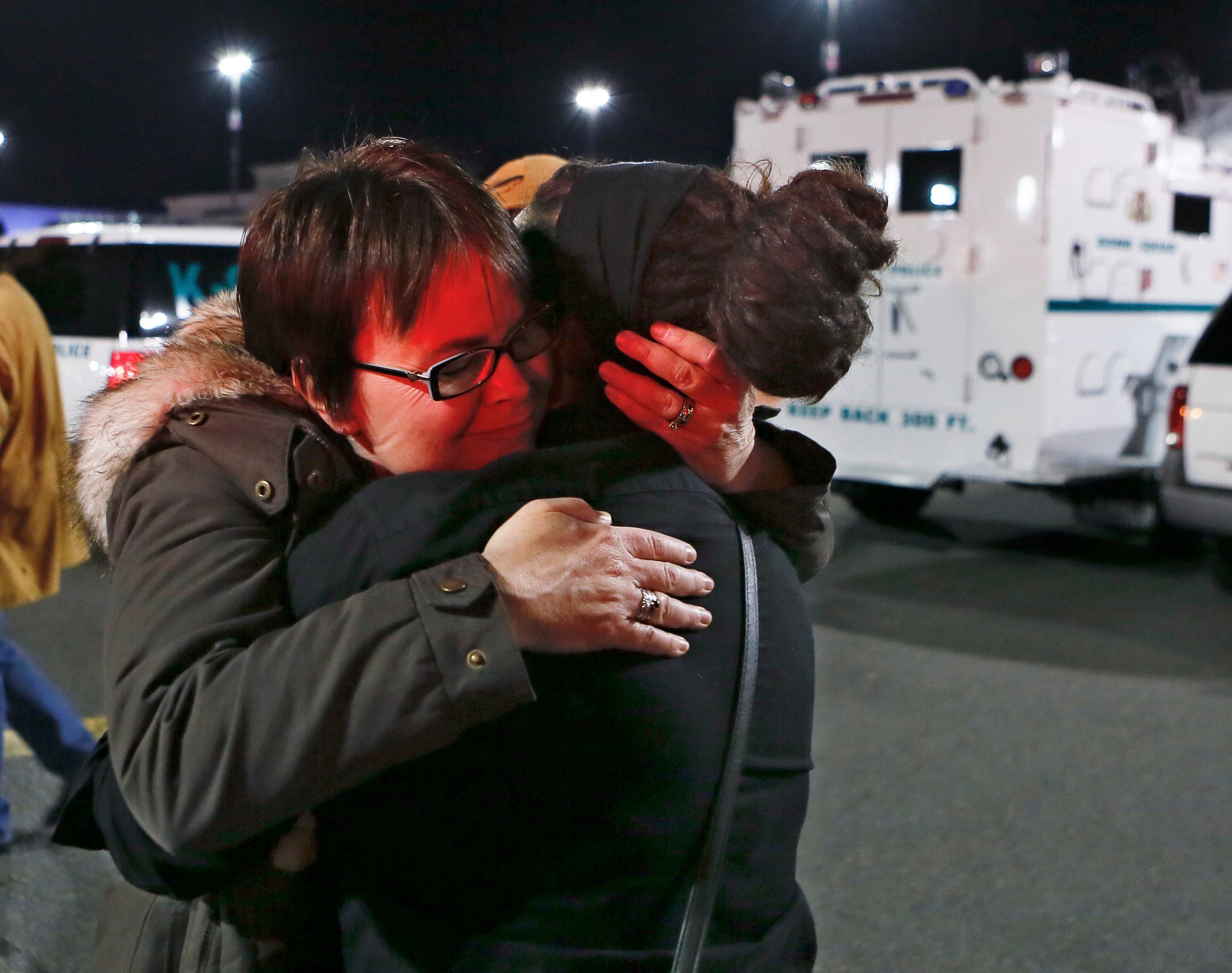 A woman, with emergency lights reflected off her face, embraces another as she exits the Garden State Plaza mall after police initiated a lockdown following reports that a gunman fired shots in the mall in Paramus, New Jersey, November 5, 2013. A person with a gun opened fire on Monday evening in the massive New Jersey shopping mall shortly before closing time, leading police to evacuate the mall and search for the shooter, but no injuries were reported, officials said. REUTERS/Ray Stubblebine