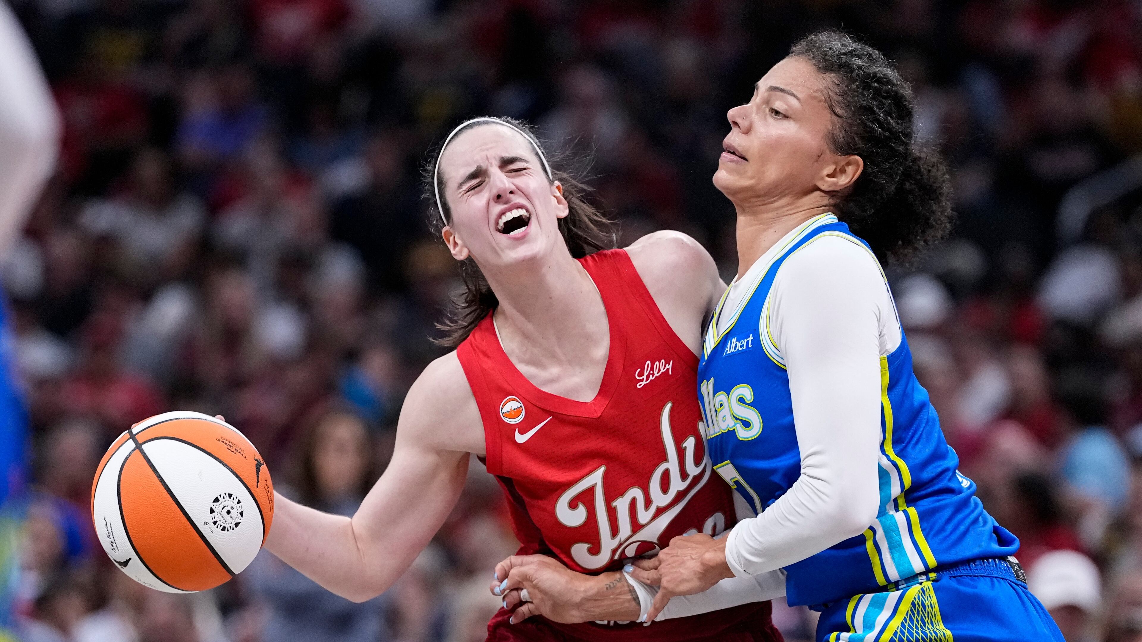 Indiana Fever guard Caitlin Clark, left, is fouled by Dallas Wings forward Alysha Clark, right, in the first half of a WNBA basketball game in Indianapolis, Friday, Aug. 14, 2026. (AP Photo/Michael Conroy)