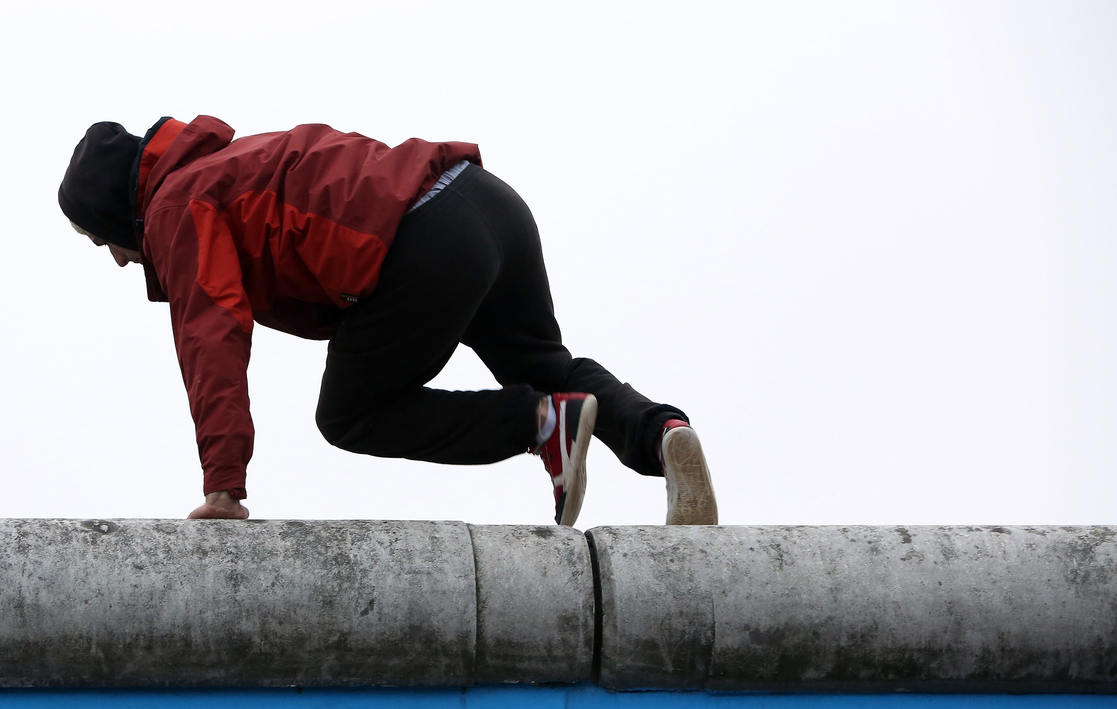A circus performer climbs atop East Side Gallery, a section of the former Berlin Wall, during celebrations for the 25th anniversary of the fall of the Wall on November 9, 2014 in Berlin, Germany. The city of Berlin is commemorating the 25th anniversary of the fall of the Berlin Wall from November 7-9 with an installation of 6,800 lamps coupled with illuminated balloons along a 15km route where the Wall once ran and divided the city into capitalist West and communist East. The fall of the Wall on November 9, 1989, was among the most powerful symbols of the revolutions that swept through the communist countries of Eastern Europe and heralded the end of the Cold War. Built by the communist authorities of East Germany in 1961, the Wall prevented East Germans from fleeing west and was equipped with guard towers and deadly traps. (Photo by Adam Berry/Getty Images)