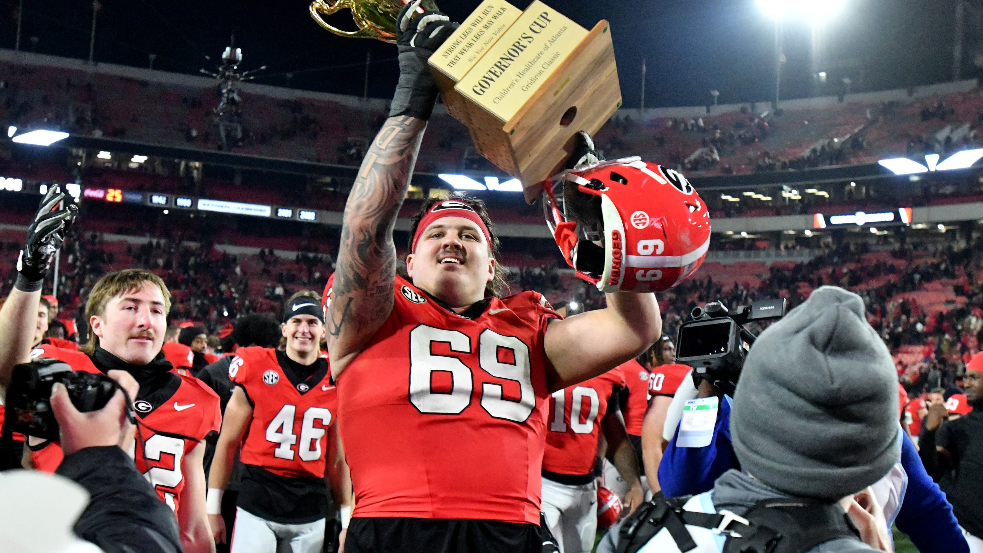 Georgia offensive lineman Tate Ratledge (69) holds up the Governor's Cup trophy after Georgia won 44-42 over Georgia Tech in eight overtimes during an NCAA football game at Sanford Stadium, Friday, November 29, 2024, in Athens. (Hyosub Shin / AJC)