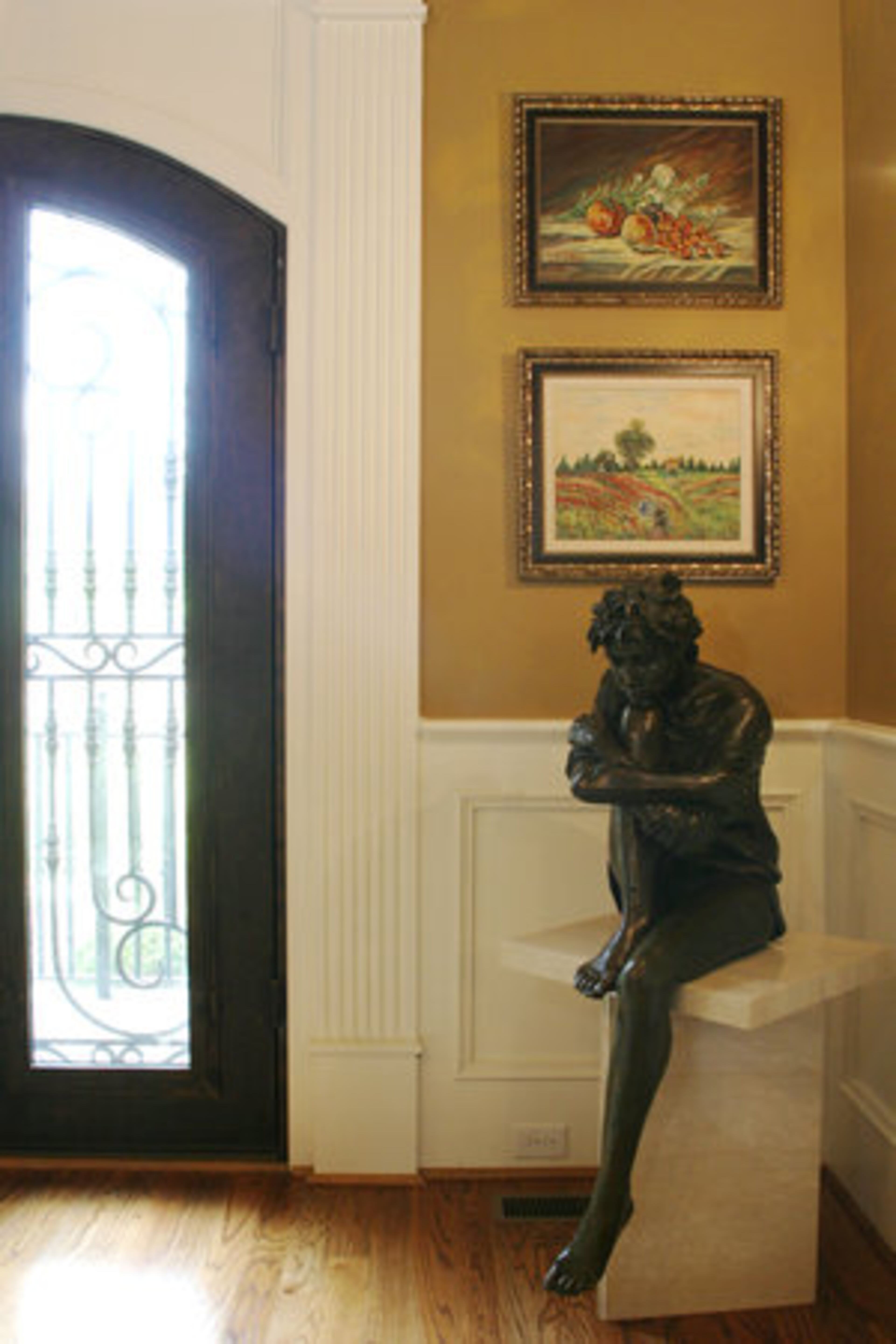 A bronze sculpture by Judith Holmes Drewry, titled the "Day Dreamer," is displayed in the dining room. It is flanked by paintings by Tom's grandmother Katie Moulouli. Her landscape paintings are of Lavadia, Greece.