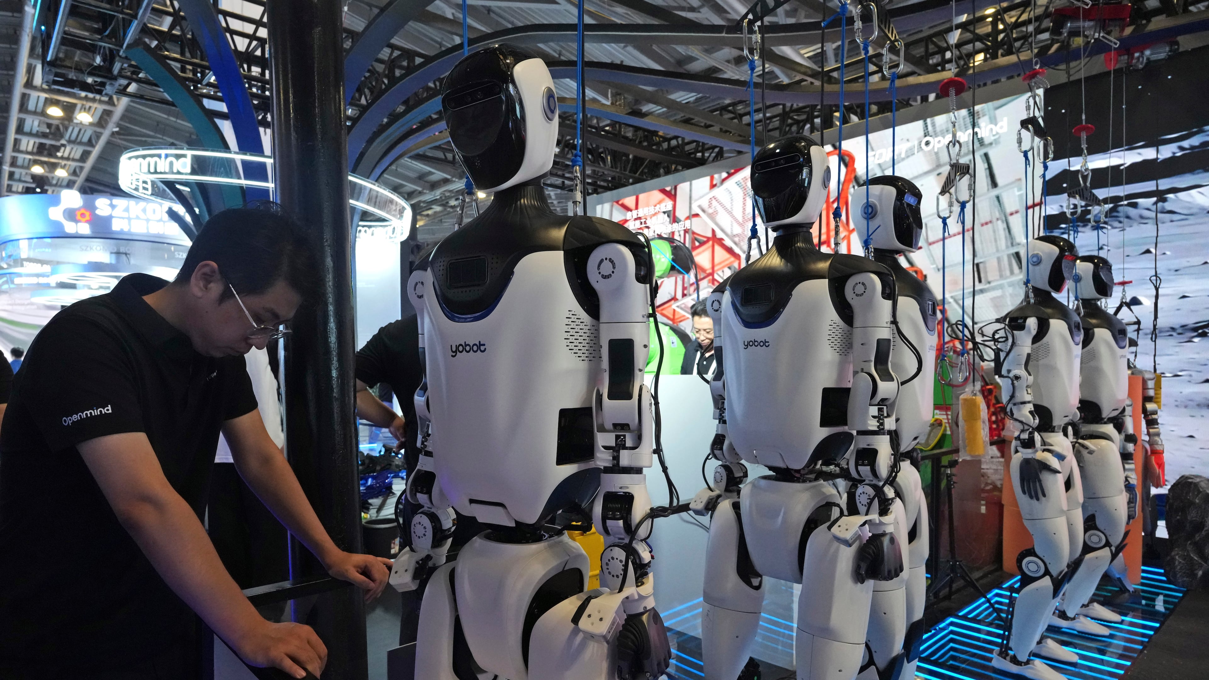 FILE - A worker reacts near a line of humanoid robots displayed at the World AI Conference in Shanghai, Friday, July 17, 2026. (AP Photo/Ng Han Guan, file)