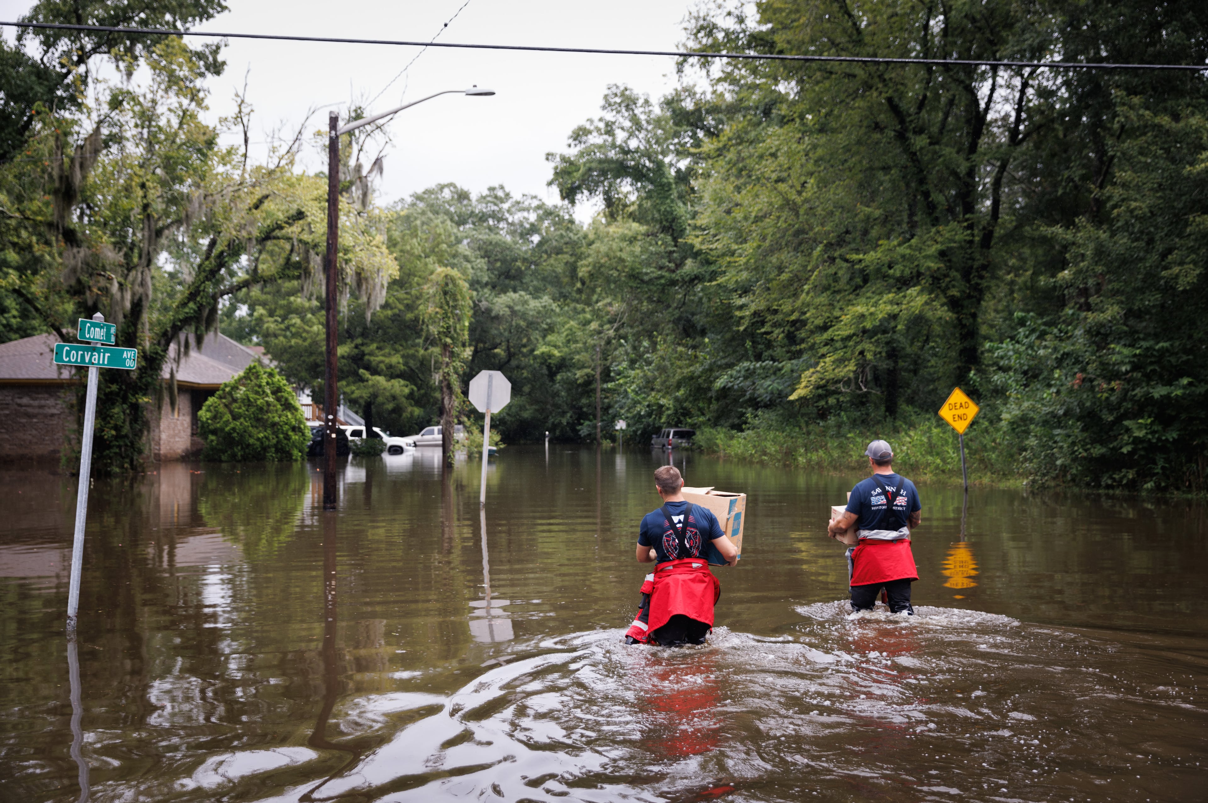 Firefighters from Savannah Fire wade into floodwaters to deliver food to residents stuck in their homes amid flooding after Tropical Storm Debbie came through Savannah, Ga., on Tuesday, Aug. 6, 2024. (Dustin Chambers/The New York Times)