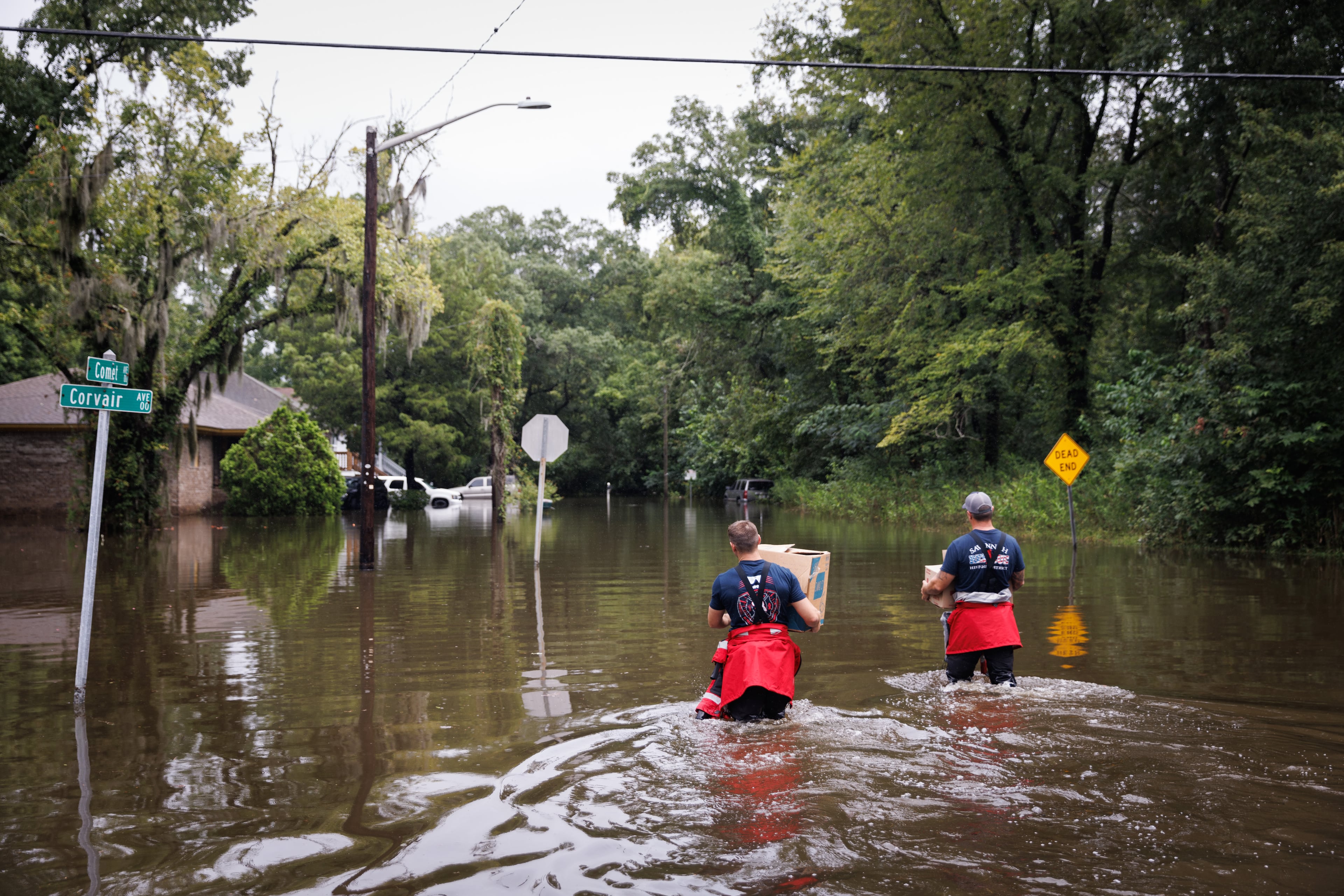 Savannah firefighters wade into floodwaters to deliver food to residents stuck in their homes amid flooding after Hurricane Debby struck Georgia in August 2024. (Dustin Chambers/The New York Times)