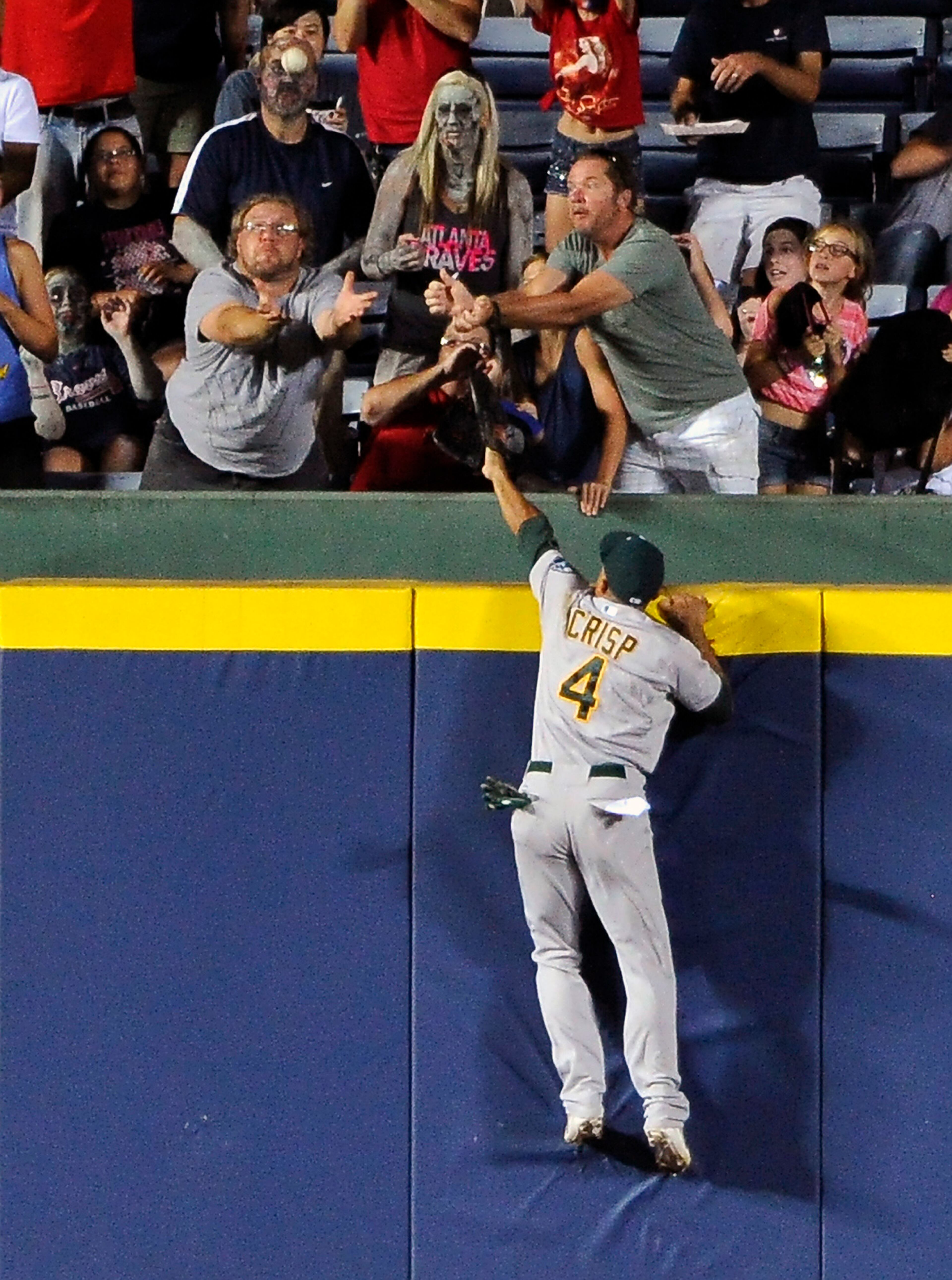 Oakland Athletics center fielder Coco Crisp (4) jumps up the wall but can't field the two-RBI home run by Atlanta Braves' Phil Gosselin during the sixth inning of a baseball game Friday, Aug. 15, 2014, in Atlanta. (AP Photo/David Tulis)