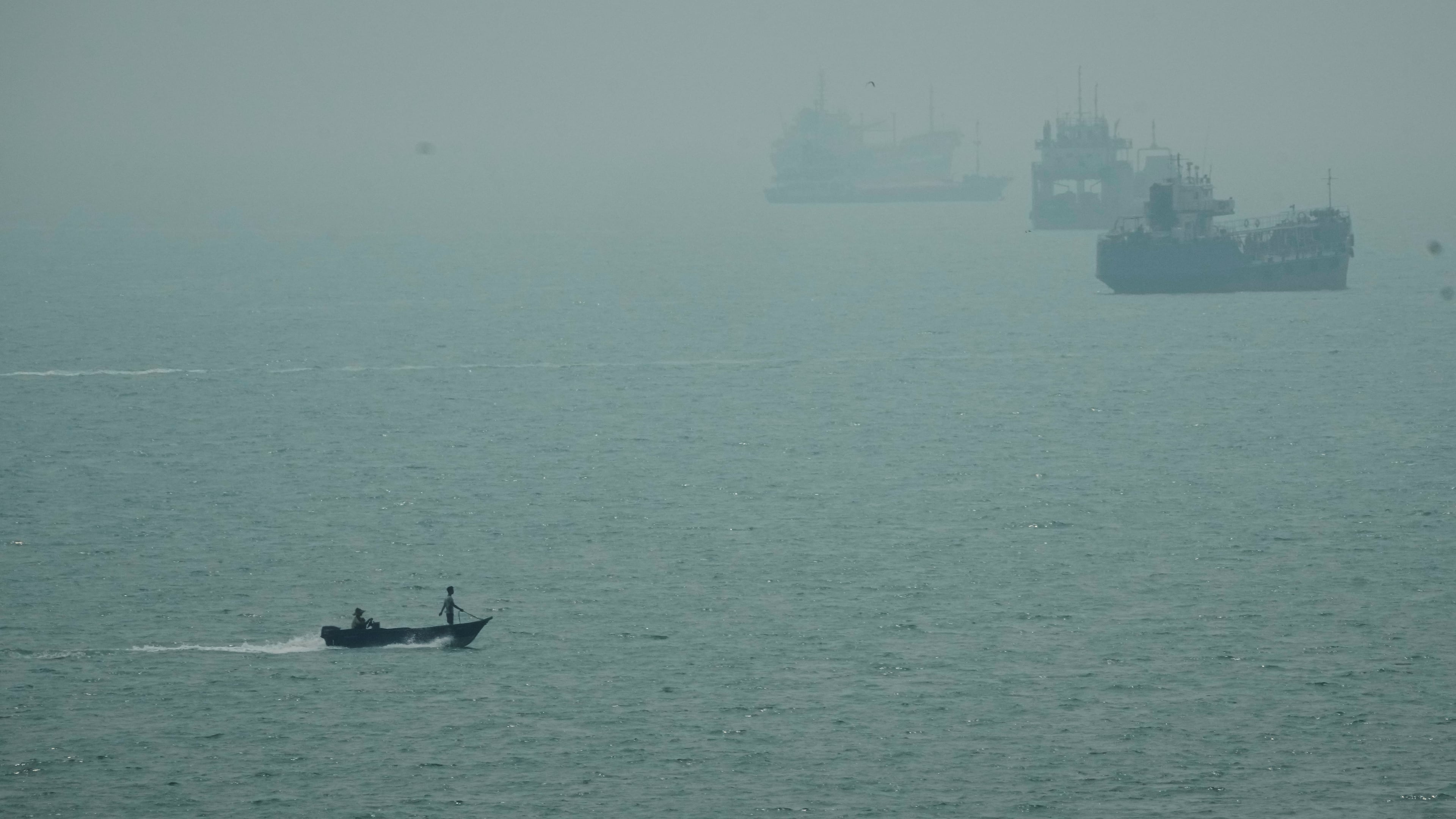 A motorboat travels past commercial vessels anchored amid haze in the Strait of Hormuz off Bandar Abbas, Iran, Monday, Sept. 7, 2026. (AP Photo/Vahid Salemi)