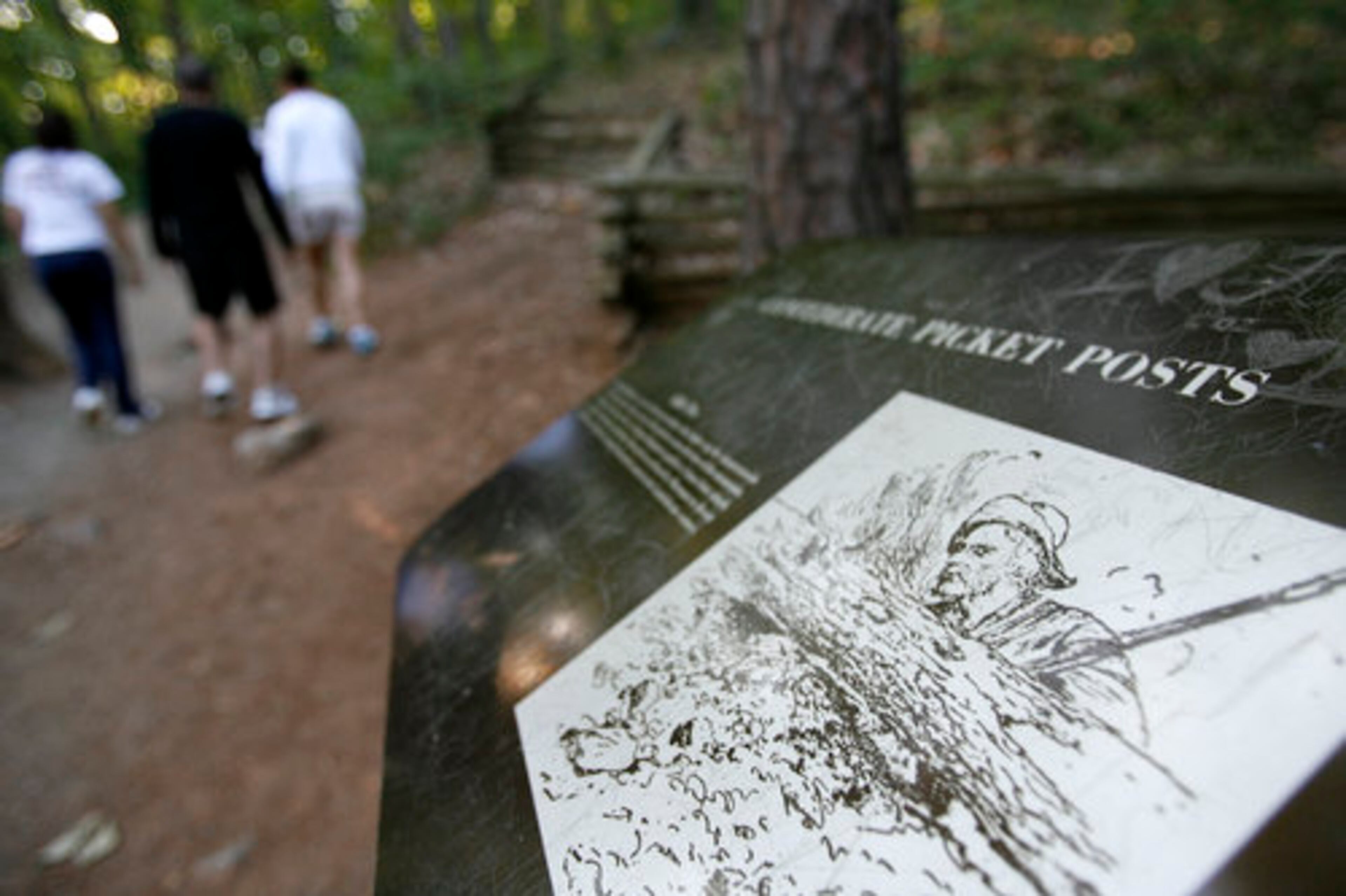 Early morning hikers walk past picket post and rifle pits along the base of the mountain trail at Kennesaw Mountain.