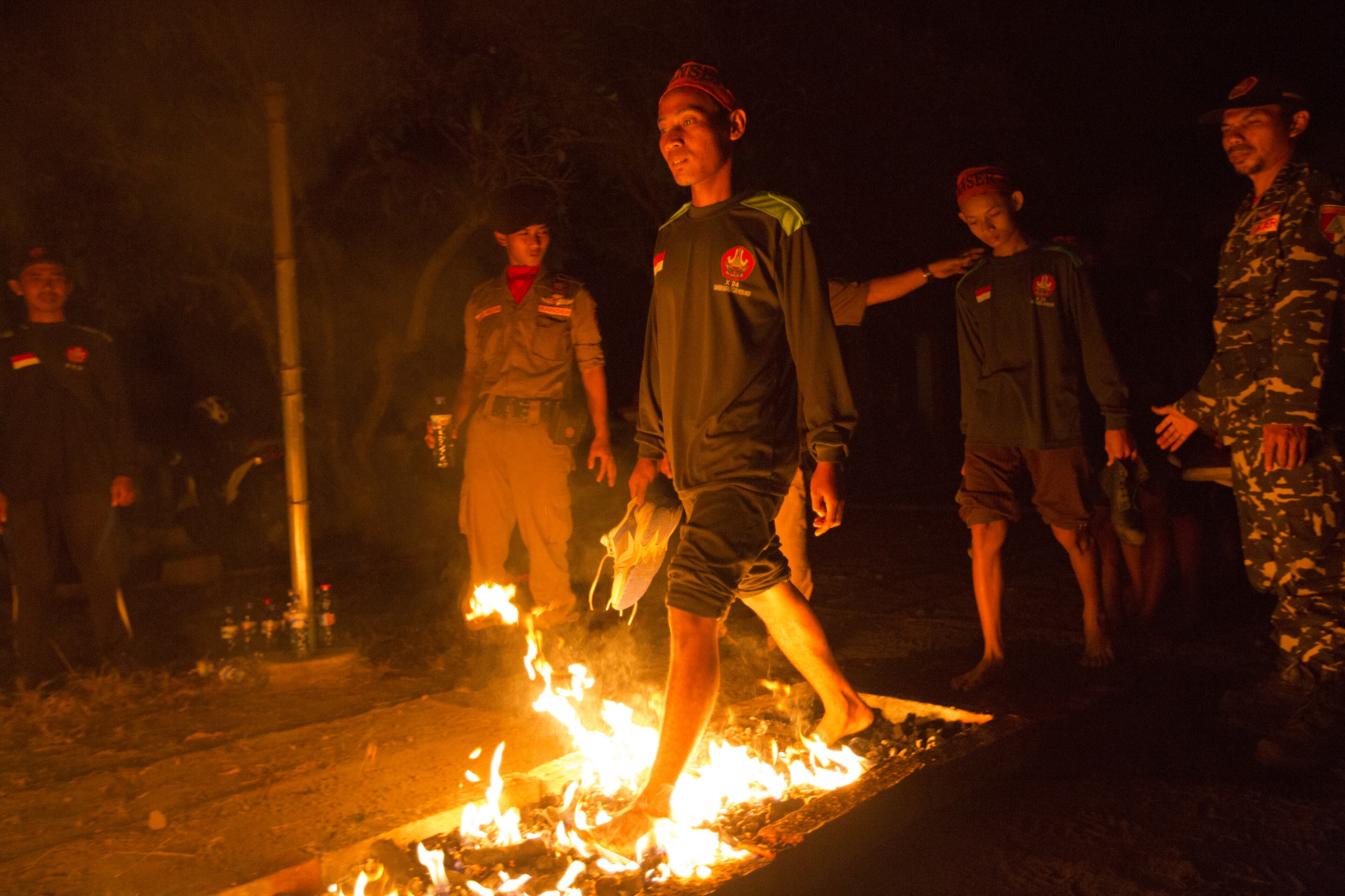 KEBUMEN, INDONESIA - JULY 22: A Banser recruit walks over burning coals as part of an initiation during a rigorous three day induction course on July 22, 2017 in Kebumen, Indonesia. Banser, the security unit of Indonesia's largest Muslim organization, Nahdatul Ulama (NU), has been on the rise to defend against Islamic fundamentalist groups as worries grow over the rise of ultra-conservative forces in the world's most populous Muslim country. Claiming a membership of 50 million, the "militant moderates" from the Nahdlatul Ulama are dedicated to supporting Indonesia's national unity and multi-religious character while combating conservative Islamic organizations, which have recently become a more vocal force in Indonesian politics and culture. Indonesia's central government recently announced a decree that will make it easier for President Joko Widodo to disband religious and civil society organizations in an apparent effort to challenge and contain hard-line Islamic groups since their rise in popularity late last year. Nahdlatul Ulama, a deeply pluralistic organization, was founded in 1926 and currently contributes in charity activities which has built hundreds of schools and hospitals. (Photo by Ed Wray/Getty Images)