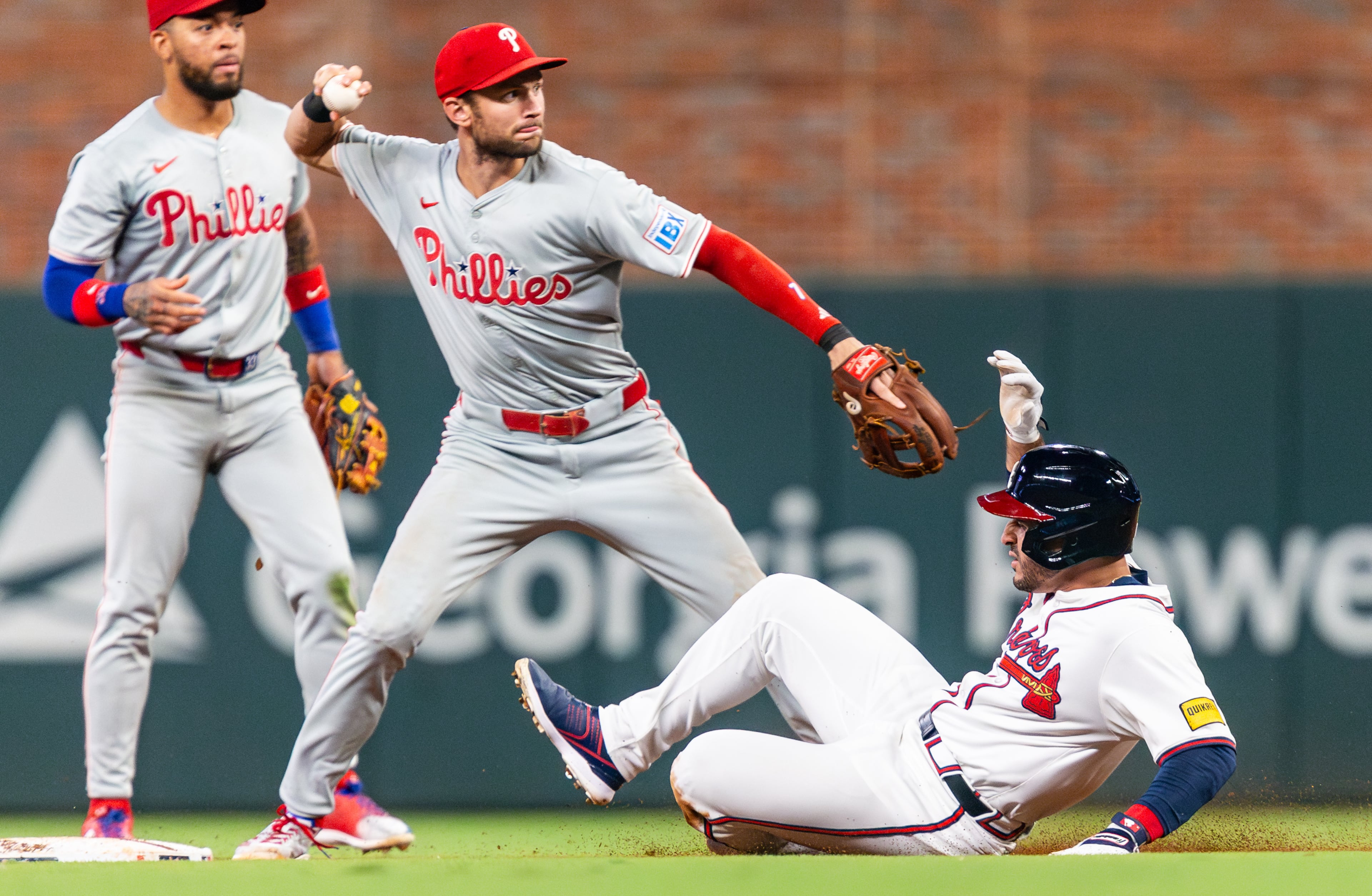 Atlanta Braves right fielder Ramón Laureano (18) slides into second base as Philadelphia Phillies shortstop Trea Turner (7) throws the ball to first base during the sixth inning at Truist Park in Atlanta on Wednesday, August 21, 2024. (Seeger Gray / AJC)