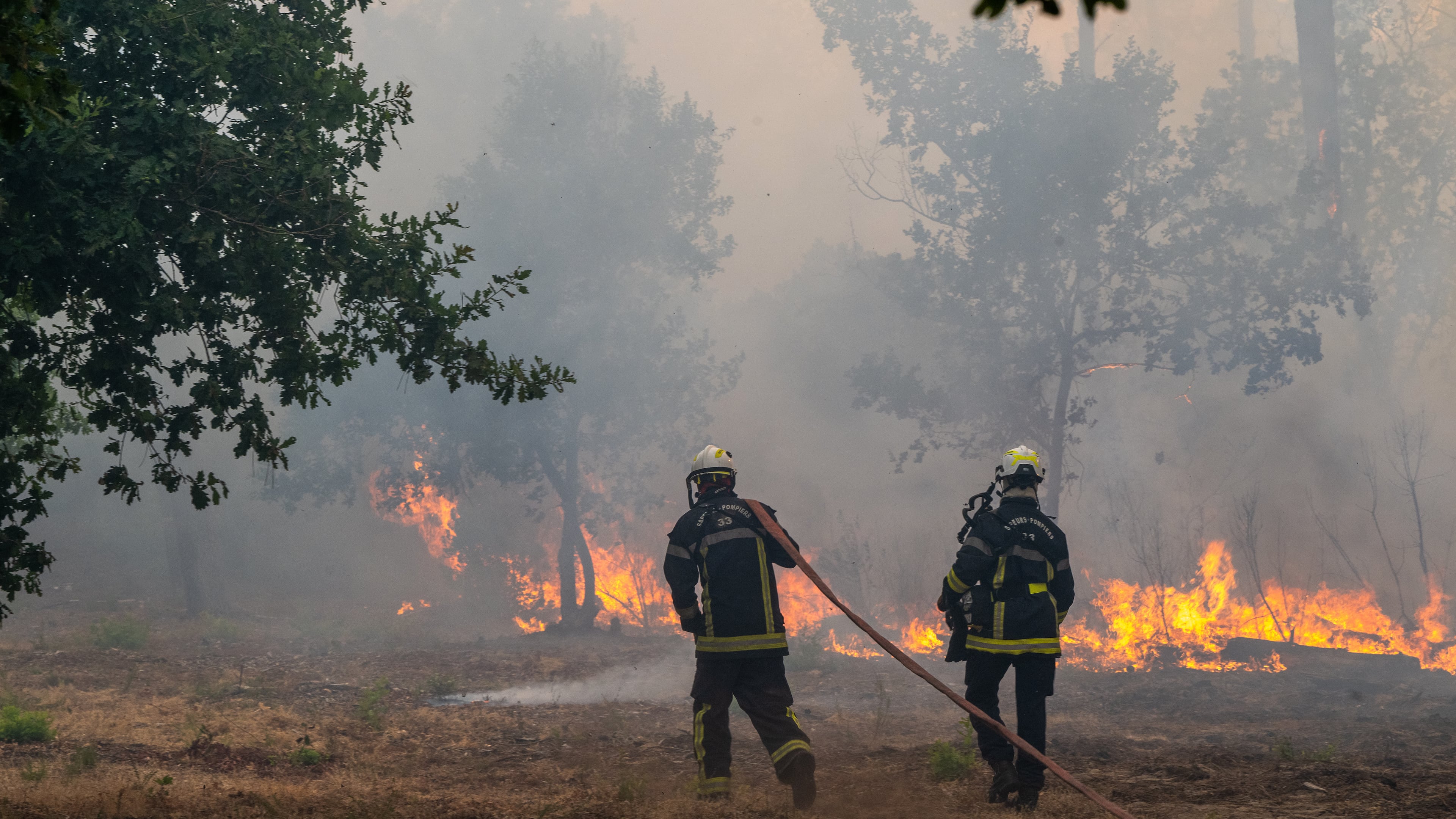 Fiirefighters spray water in a burning forest in the Lège-Cap-Ferret region, western France, Friday, July 24, 2026. (AP Photo/Caroline Blumberg)