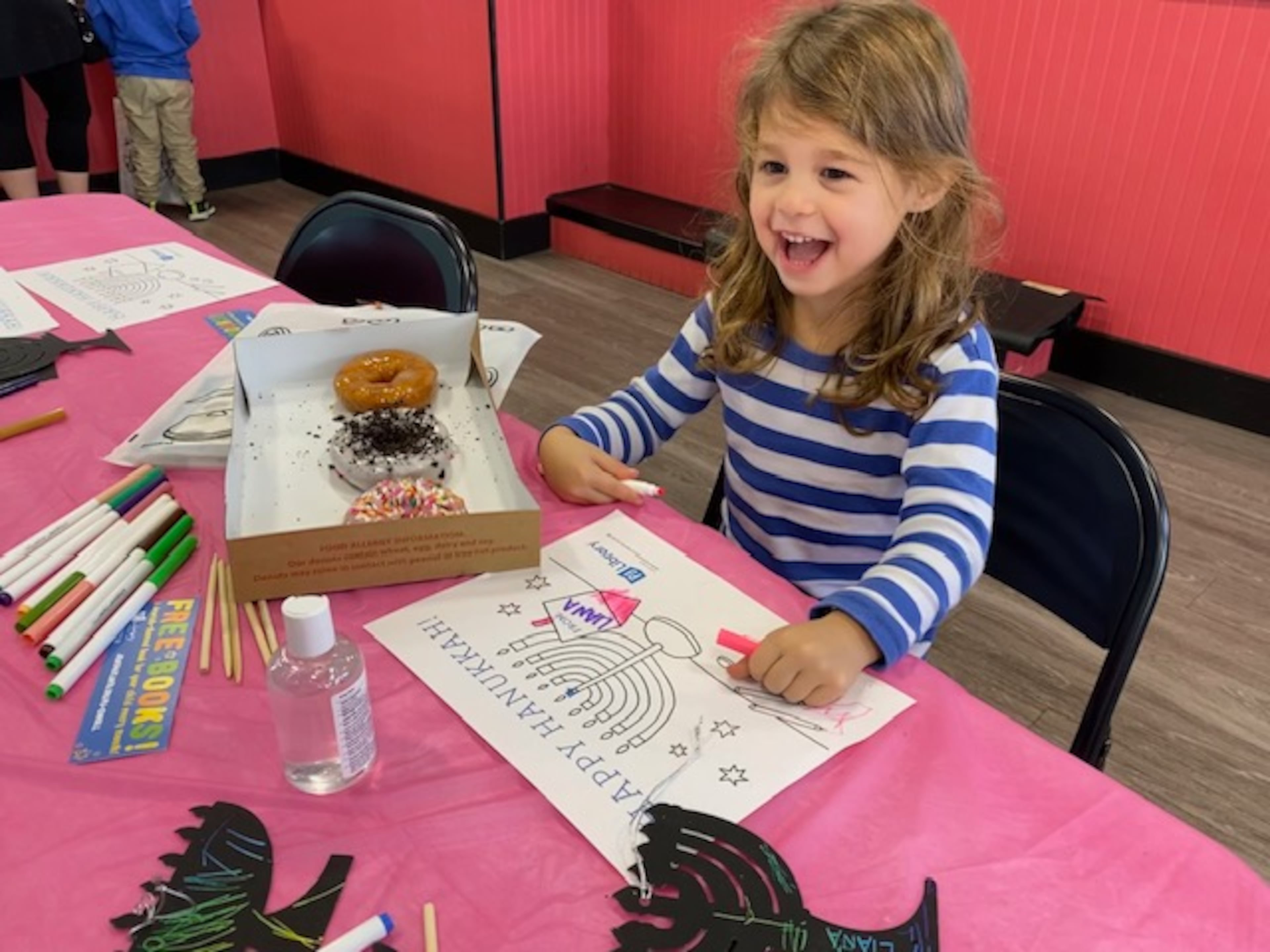 A young girl enjoys donuts and coloring a menorah at a past Donuts and Dreidels event held by the Jewish Federation of Greater Atlanta. (Courtesy of the Jewish Federation of Greater Atlanta)