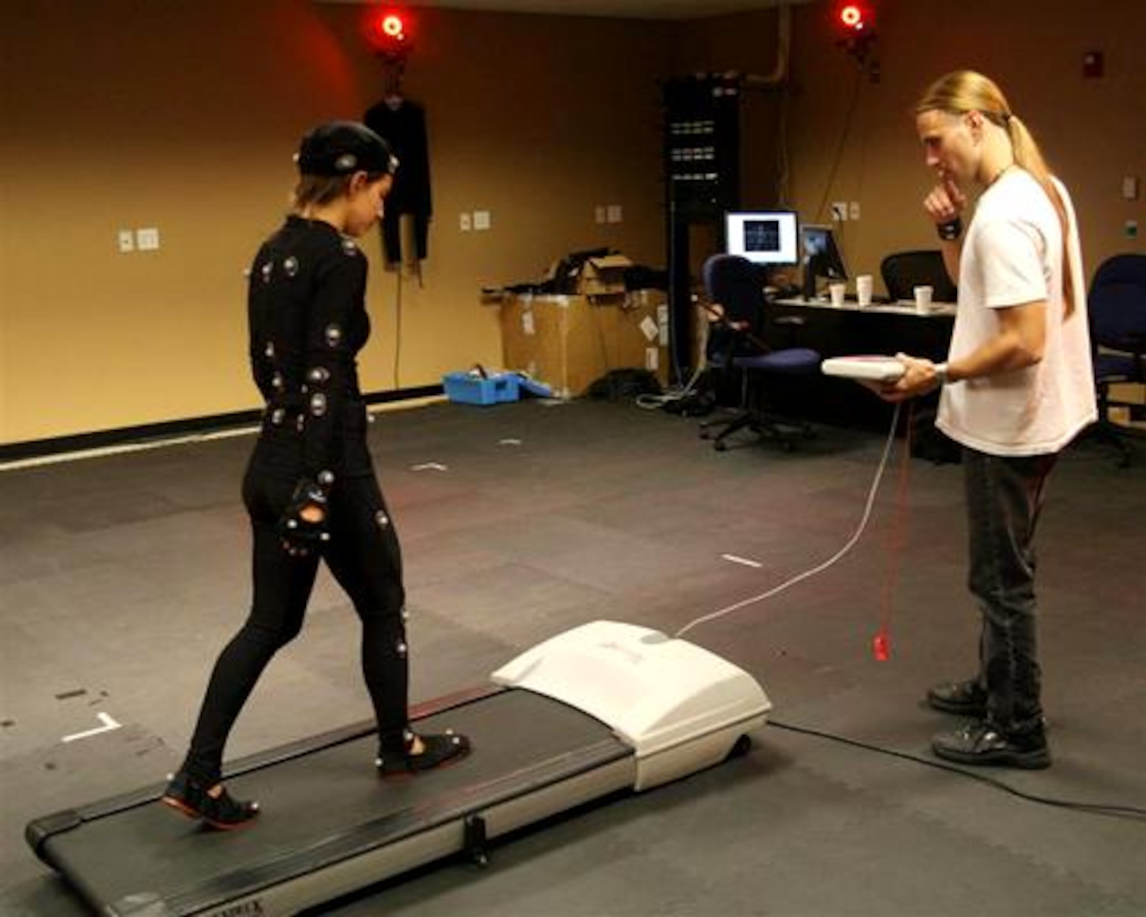 Daniel Lilleberg(right)sets up a customized treadmill for Michal Adam to walk on during a motion capture session at Hi-Rez Studios in Alpharetta. Adam dressed in a costume with "markers" on it for video used in computer animation. Multiple cameras around the room capture the "markers" on Adam to create a three dimensional image.