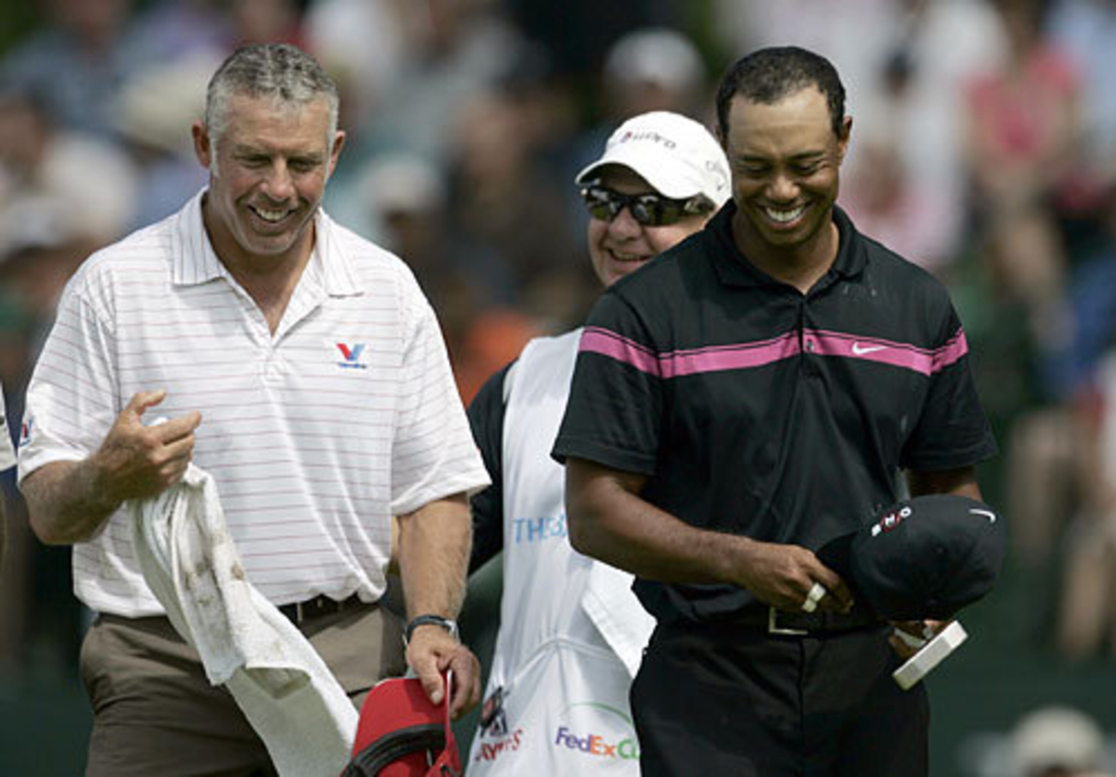 Tiger Woods, right, and his caddie Steve Williams, left, walk off the 18th green smiling after woods sank a birdie putt to finish at 6-under par during the first round of The Barclays.