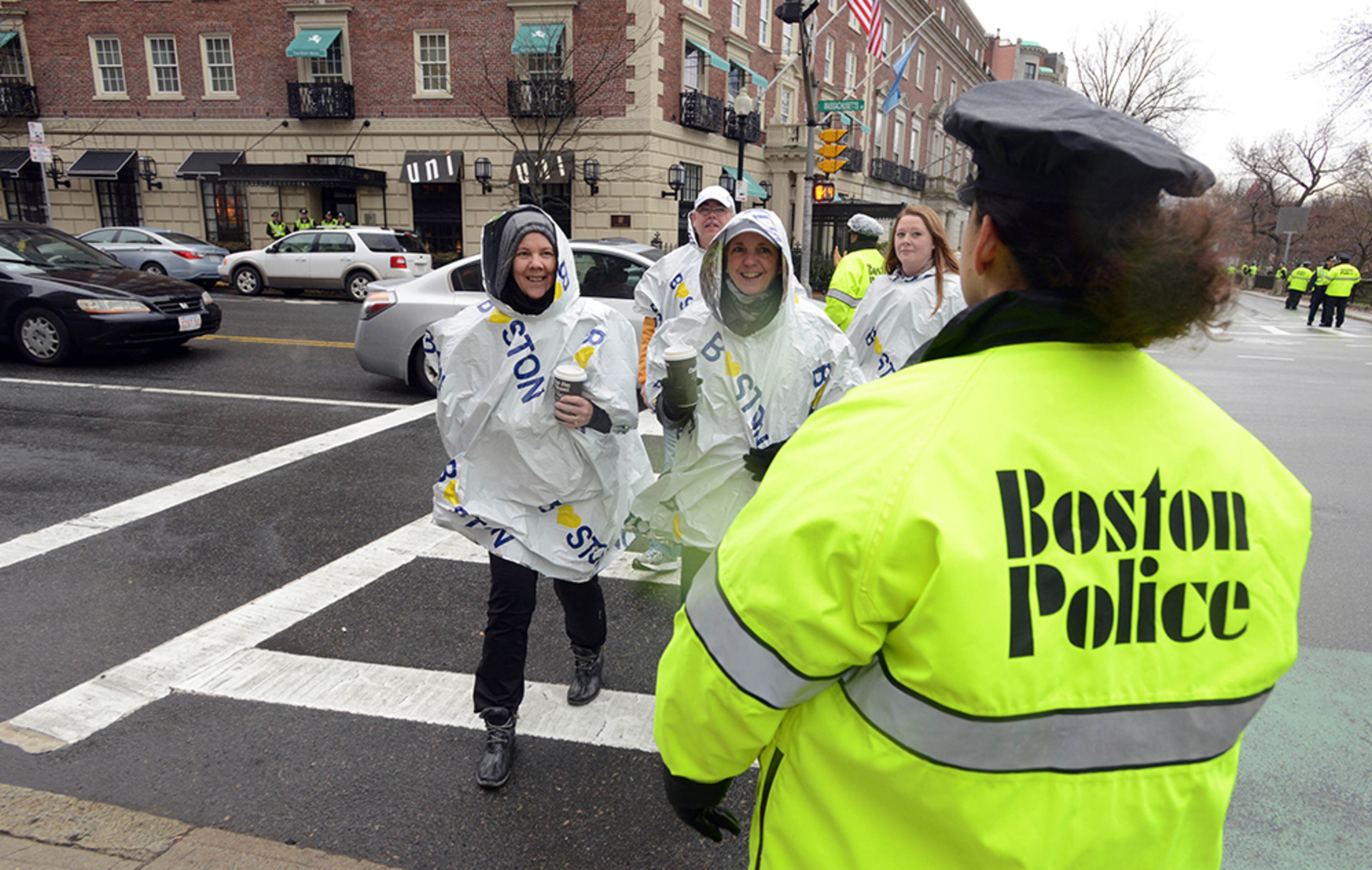 A group of people in panchos walk past a Boston Police officer on Commonwealth Avenue near Kenmore Square as the Boston Marathon prepares to get under way April 20, 2015, in Boston. This is the 119th running of the Boston Marathon.