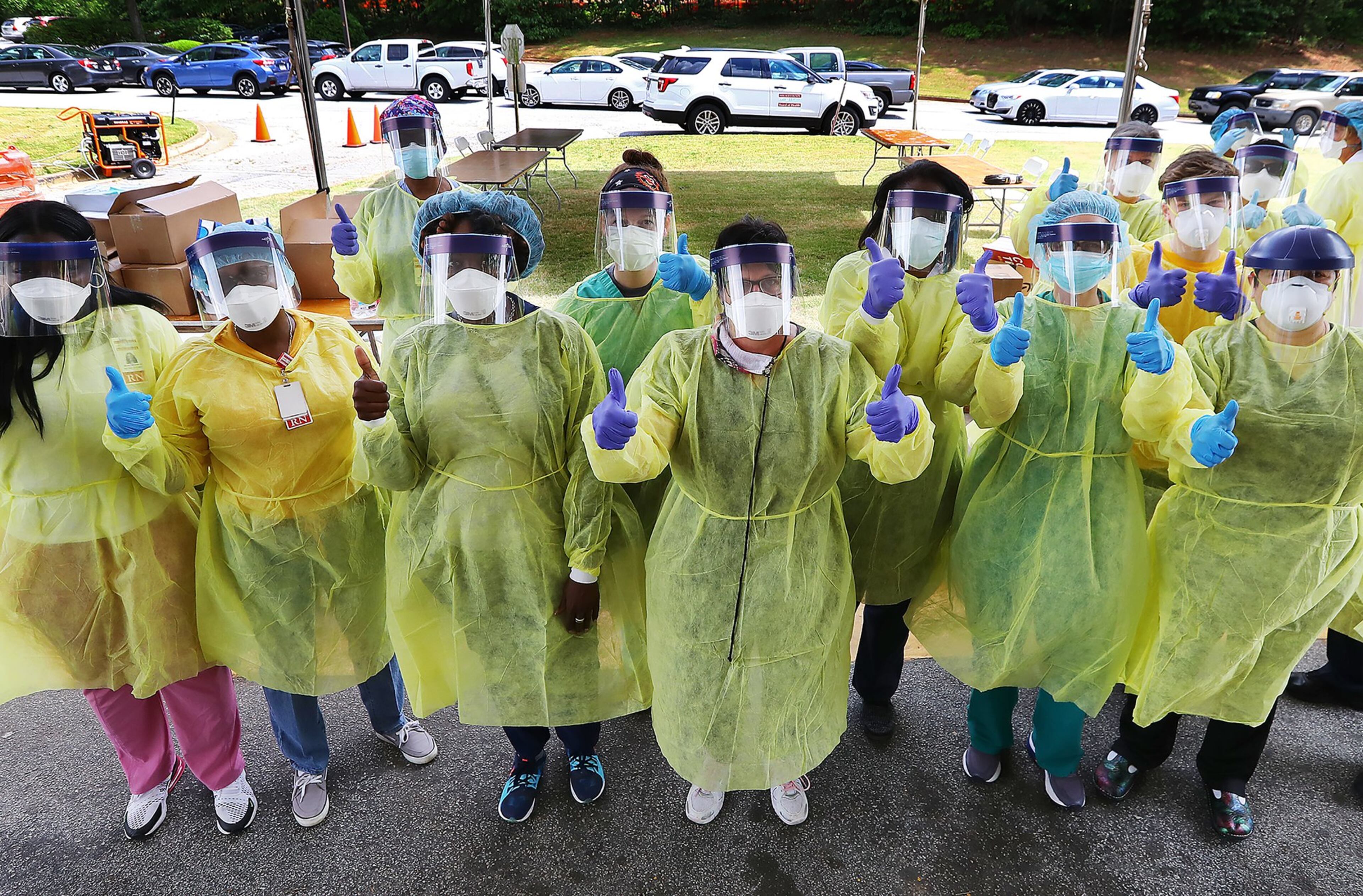 Some of the more than two dozen specimen collection volunteers give the thumbs-up as they begin hundreds of free COVID-19 tests at a pop-up site at the House of Hope in Decatur on May 4, 2020. More than 200 motorists arrived for the opening. (Curtis Compton/ccompton@ajc.com)