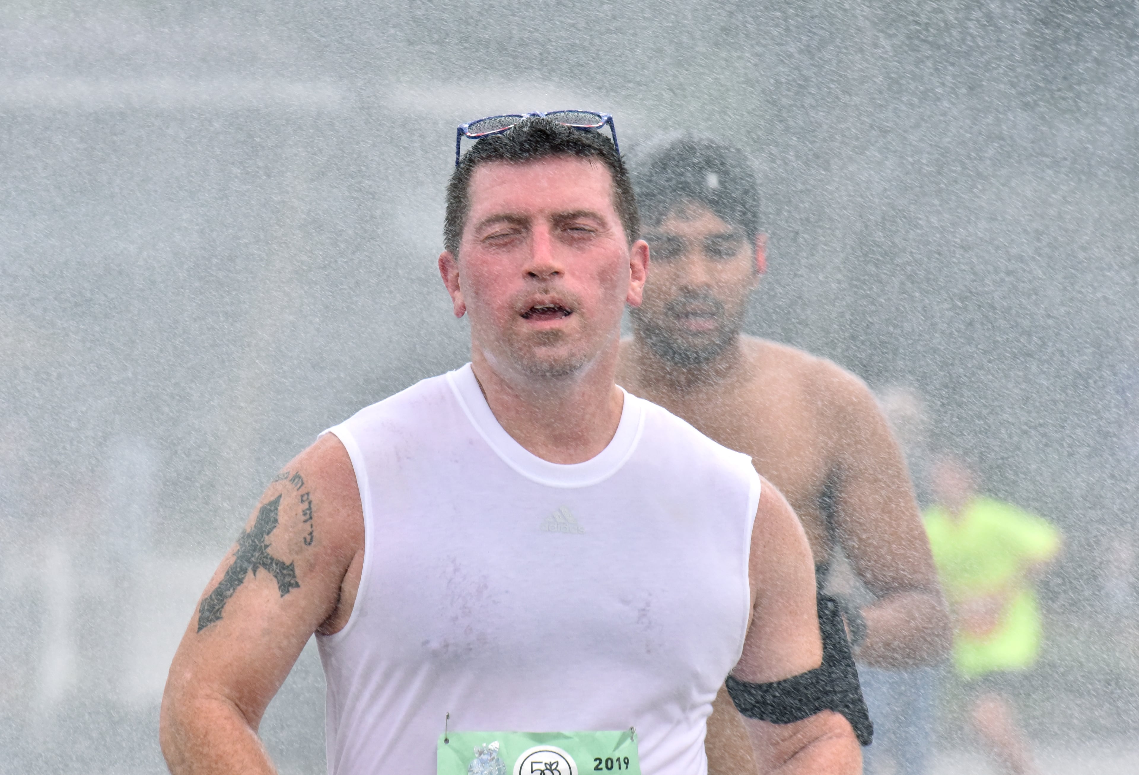 A runner cools off with mist as he makes his way down Peachtree Road during the 50th AJC Peachtree Road Race on Thursday, July 4, 2019. (Hyosub Shin / Hyosub.Shin@ajc.com)