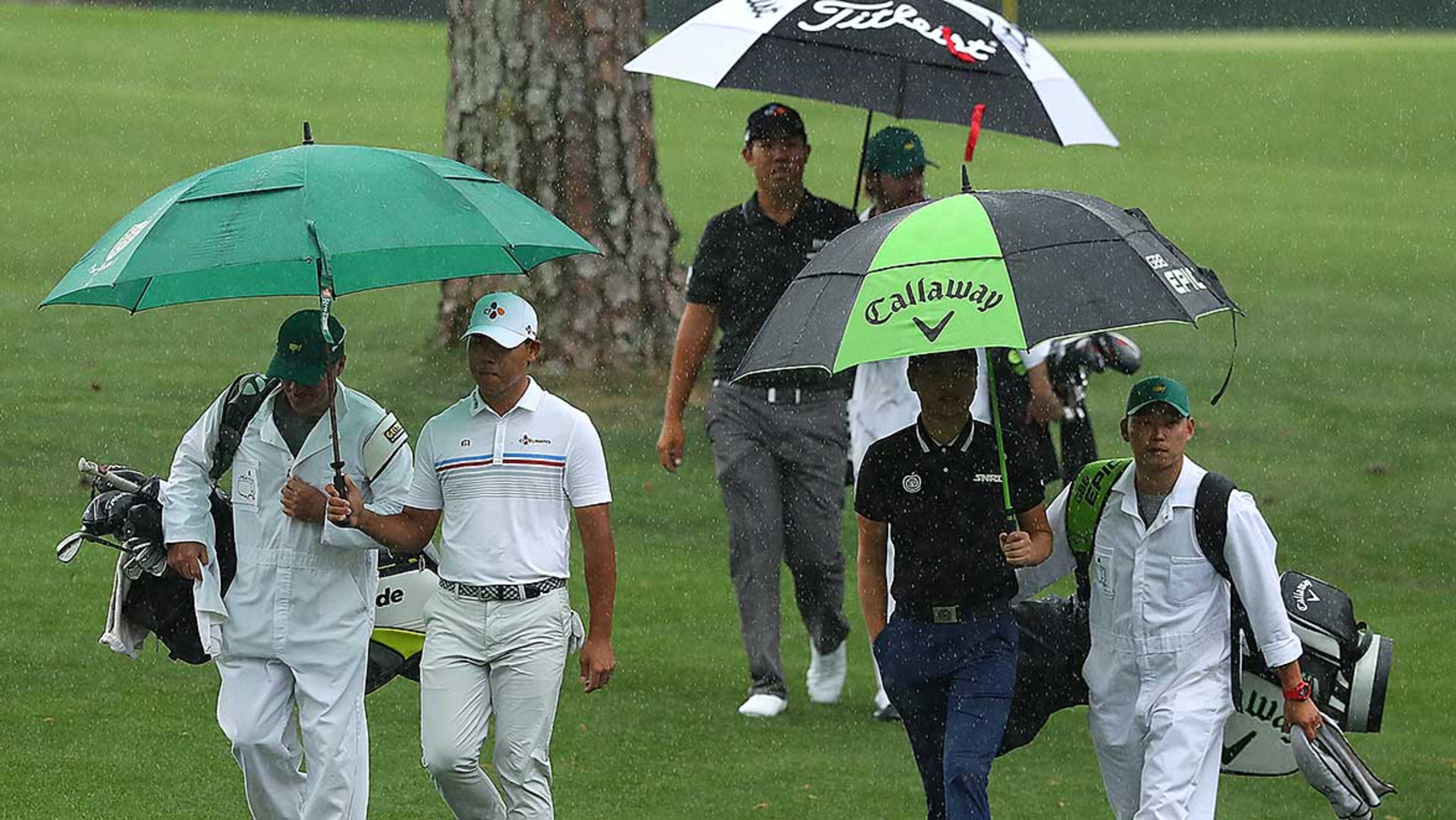 Rainy day in Augusta: Korean golfers Si Woo Kim (from left), Byeong Hun An and Jeunghun Wang walk to the 16th green as rain moves in during their practice round for the Masters at Augusta National Golf Club Monday.