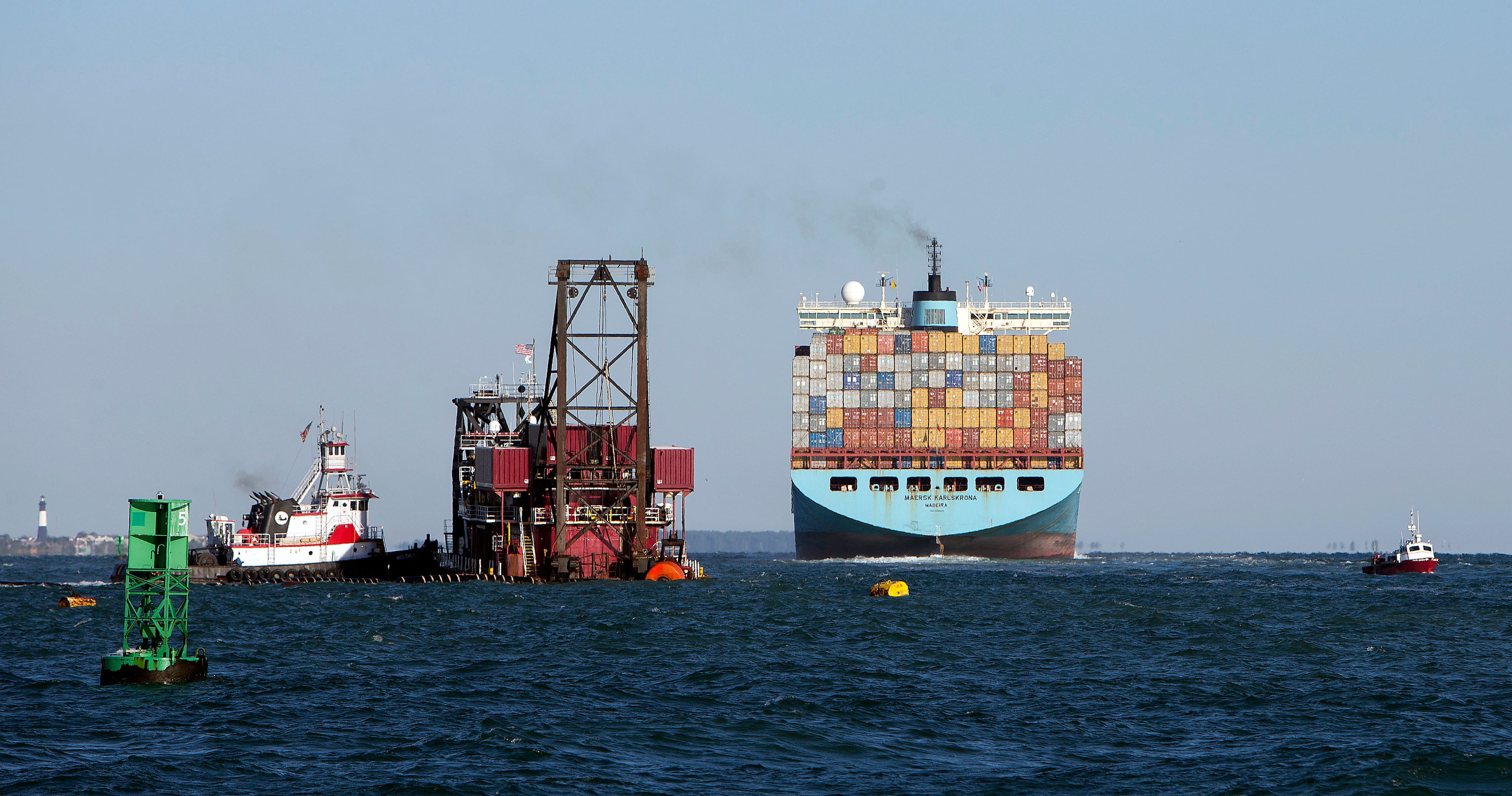 A dredge ship works in the Savannah River off the coast of Tybee Island as a cargo ship passes during a harbor deepening project completed in 2022. (AJC file photo)