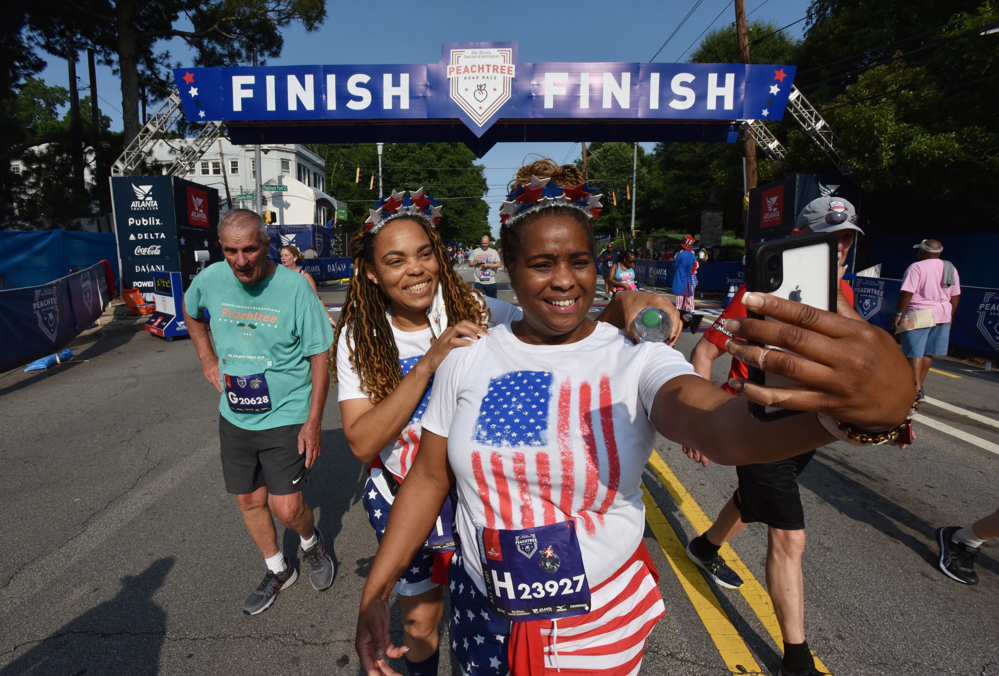 July 3, 2021 Atlanta - Runners take a selfie after crossing the finish line during the first day of 2021 Atlanta Journal-Constitution Peachtree Road Race on Saturday, July 3, 2021. (Hyosub Shin / Hyosub.Shin@ajc.com)