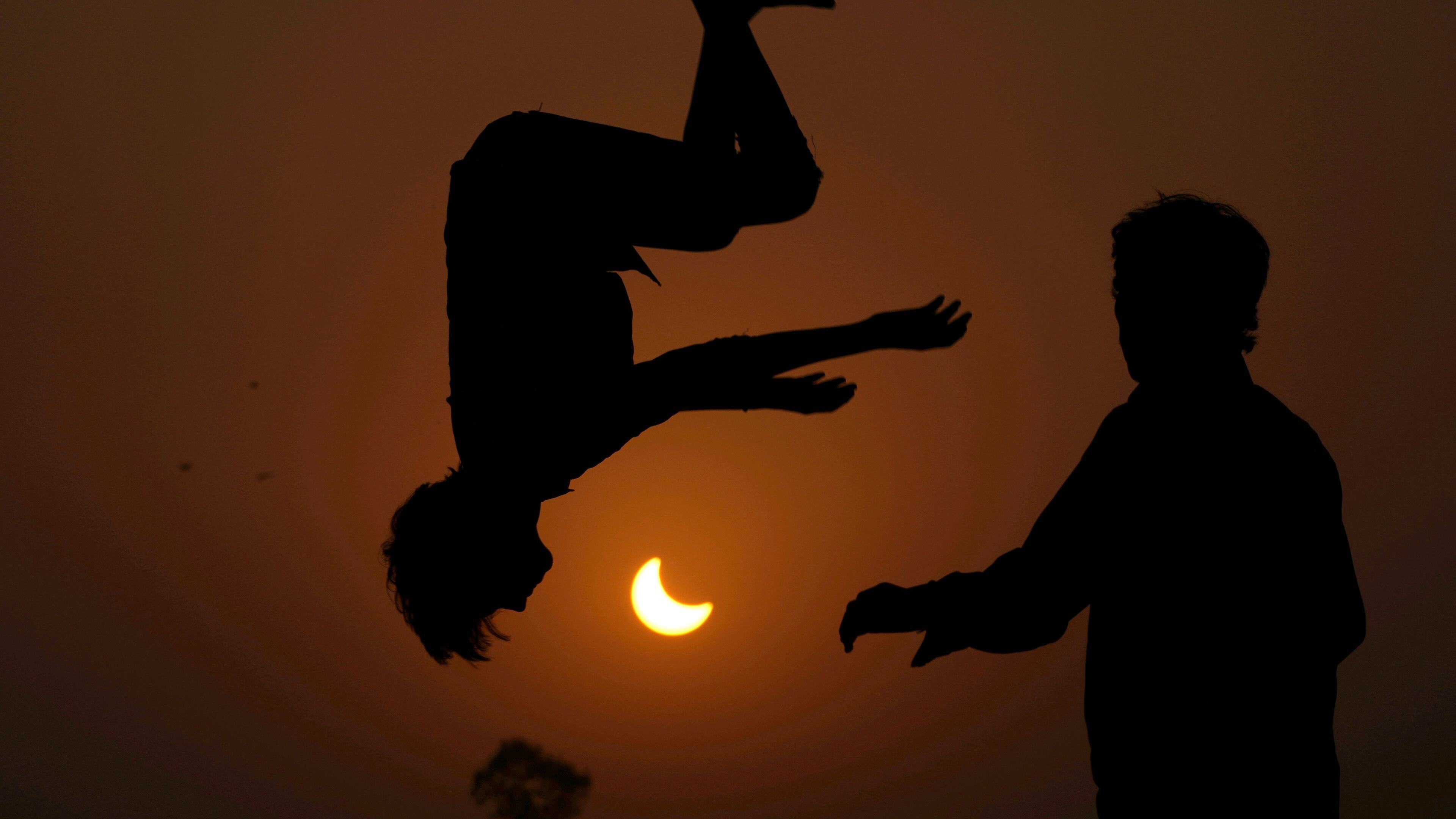 FILE - The partial solar eclipse is framed by youngsters jumping on a trampoline in the outskirts of Lahore, Pakistan, Oct. 25, 2022. (AP Photo/K.M. Chaudary, File)